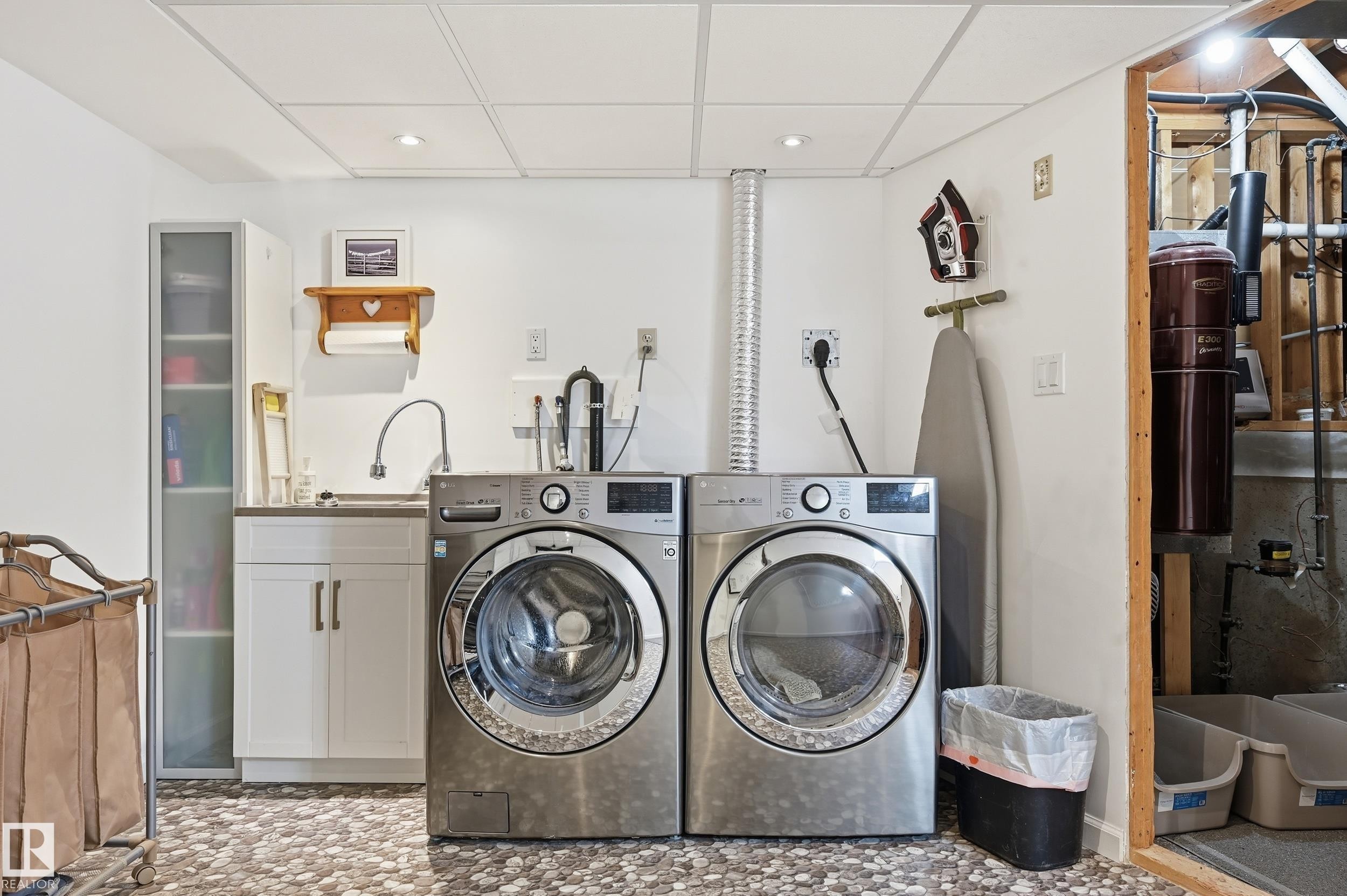 Dedicated laundry area featuring a utility sink, white cabinetry, and a pebble-patterned floor - 85 Arlington Drive, St. Albert, AB - Indoor Photo Showing Laundry Room