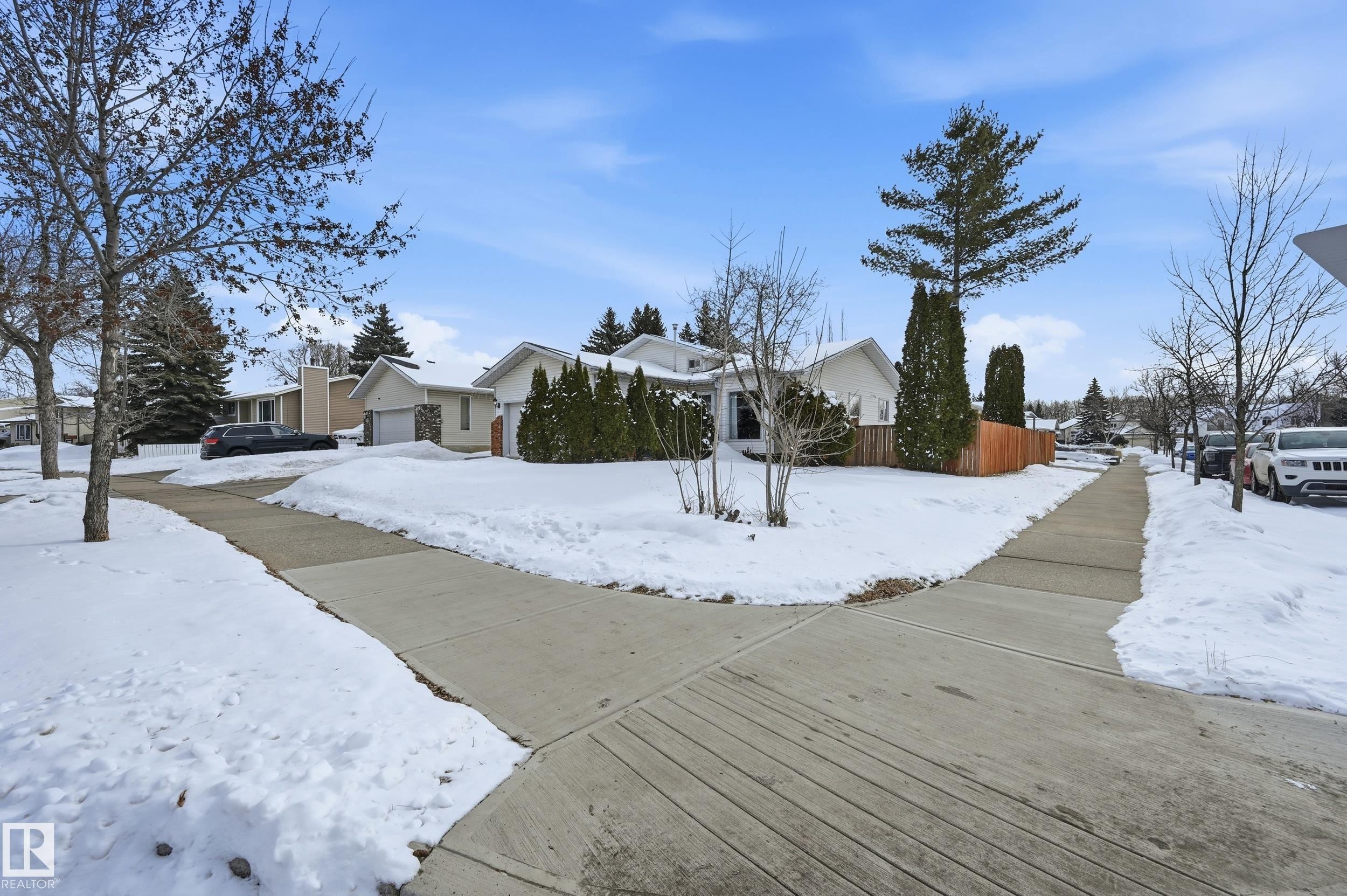This property features a well-maintained exterior with a white facade and an attached garage - 85 Arlington Drive, St. Albert, AB - Outdoor