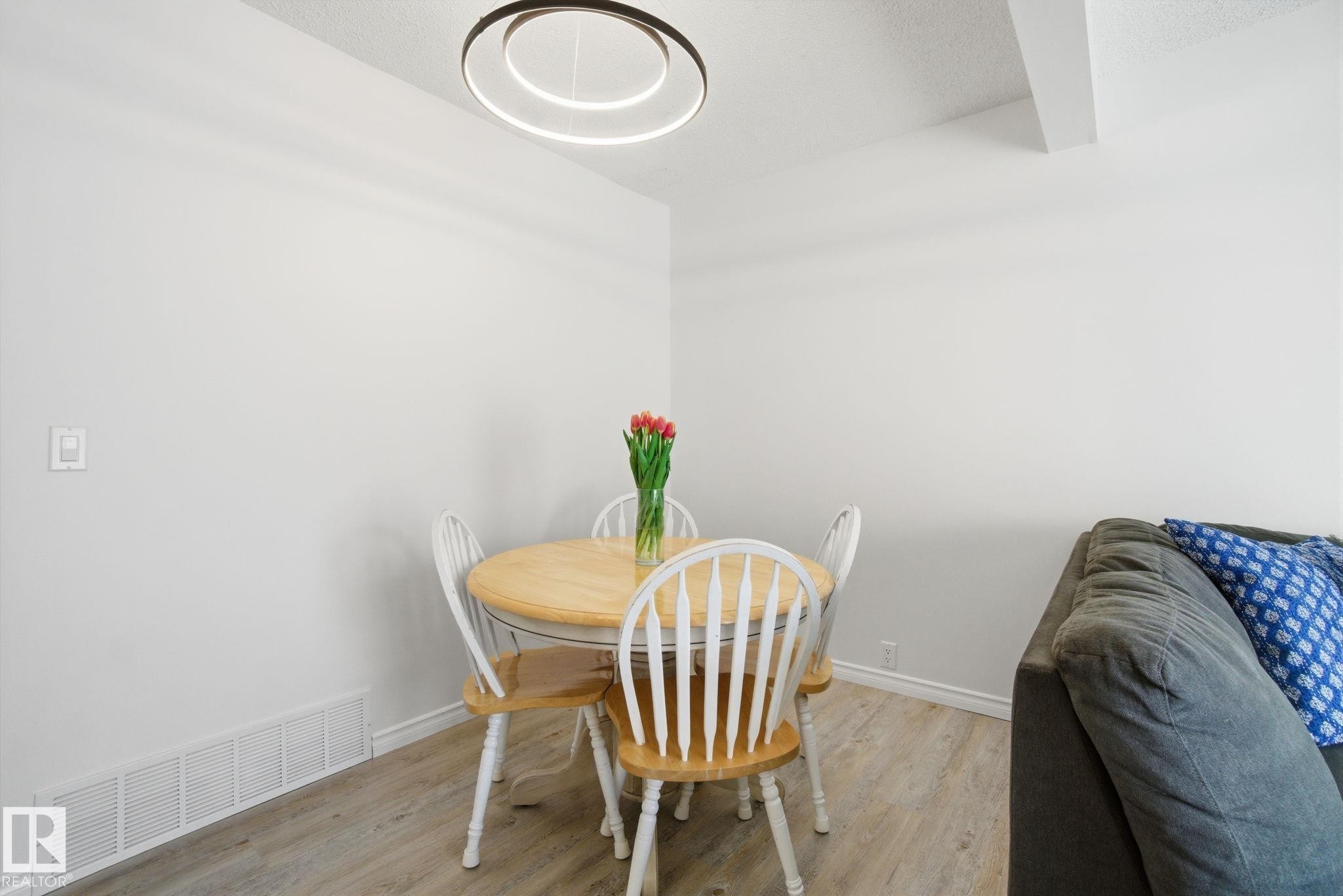 Dining area featuring light wood flooring and a modern circular light fixture - 29 9619 180 Street, Edmonton, AB - Indoor Photo Showing Dining Room