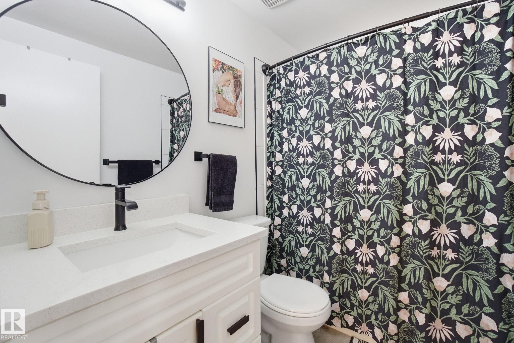 Bathroom vanity with a white countertop and a round mirror - 29 9619 180 Street, Edmonton, AB - Indoor Photo Showing Bathroom