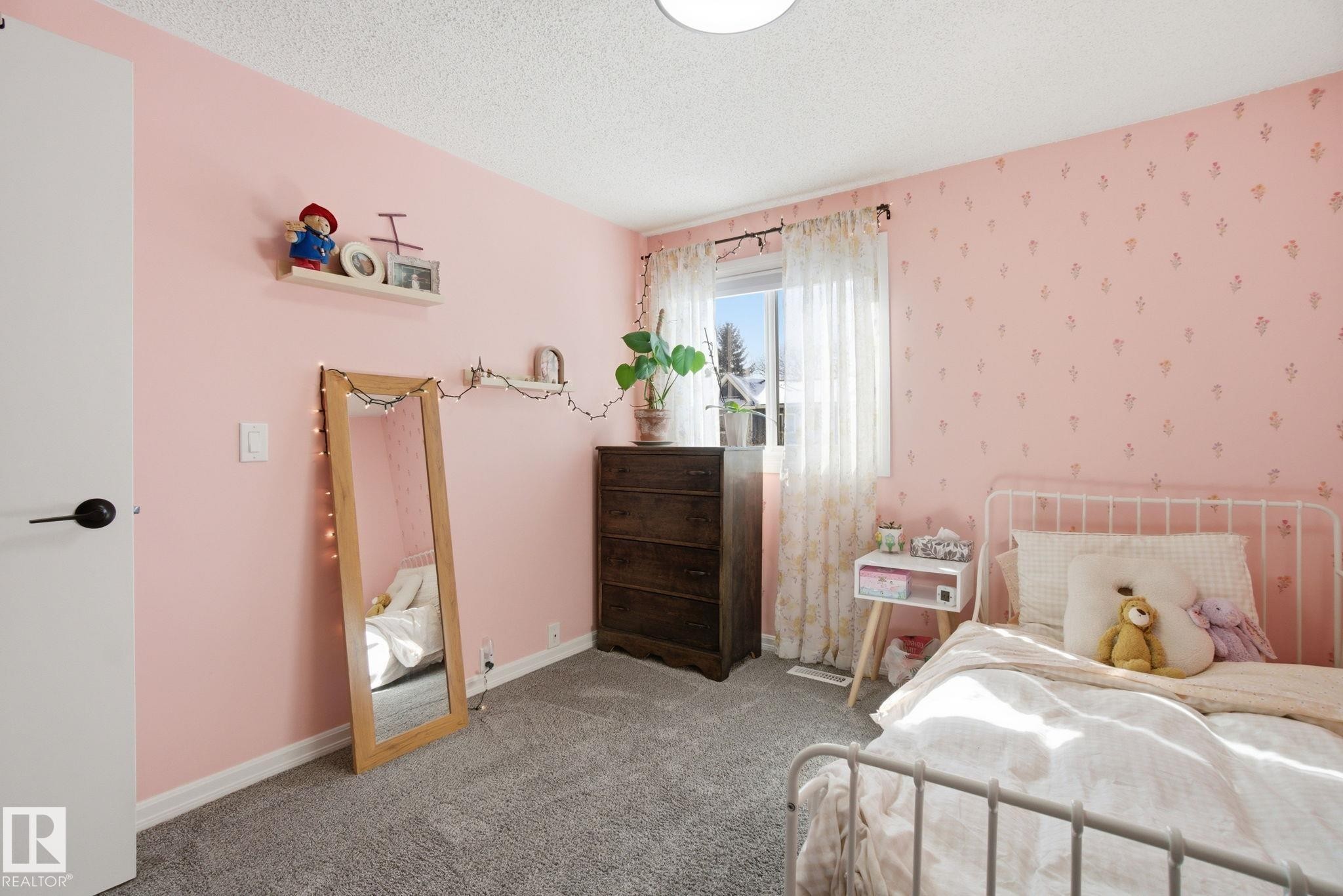 This room features textured carpeting, a window with sheer curtains, and a white metal bed frame - 29 9619 180 Street, Edmonton, AB - Indoor Photo Showing Bedroom