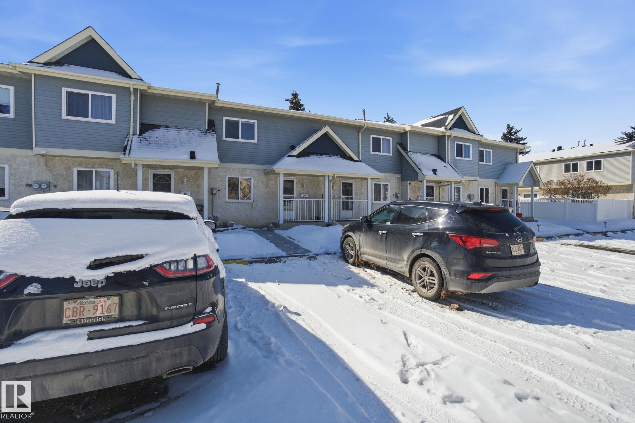 The property features a multi-level structure with light-colored siding and a contrasting darker colored upper facade - 29 9619 180 Street, Edmonton, AB - Outdoor