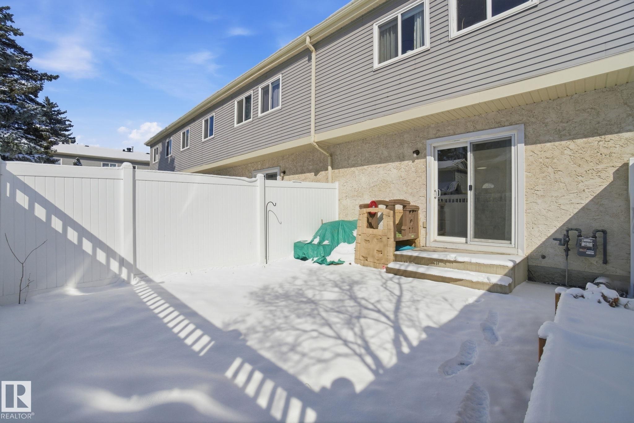 The property features a private fenced yard with a patio area and direct access to the interior via a sliding glass door - 29 9619 180 Street, Edmonton, AB - Outdoor