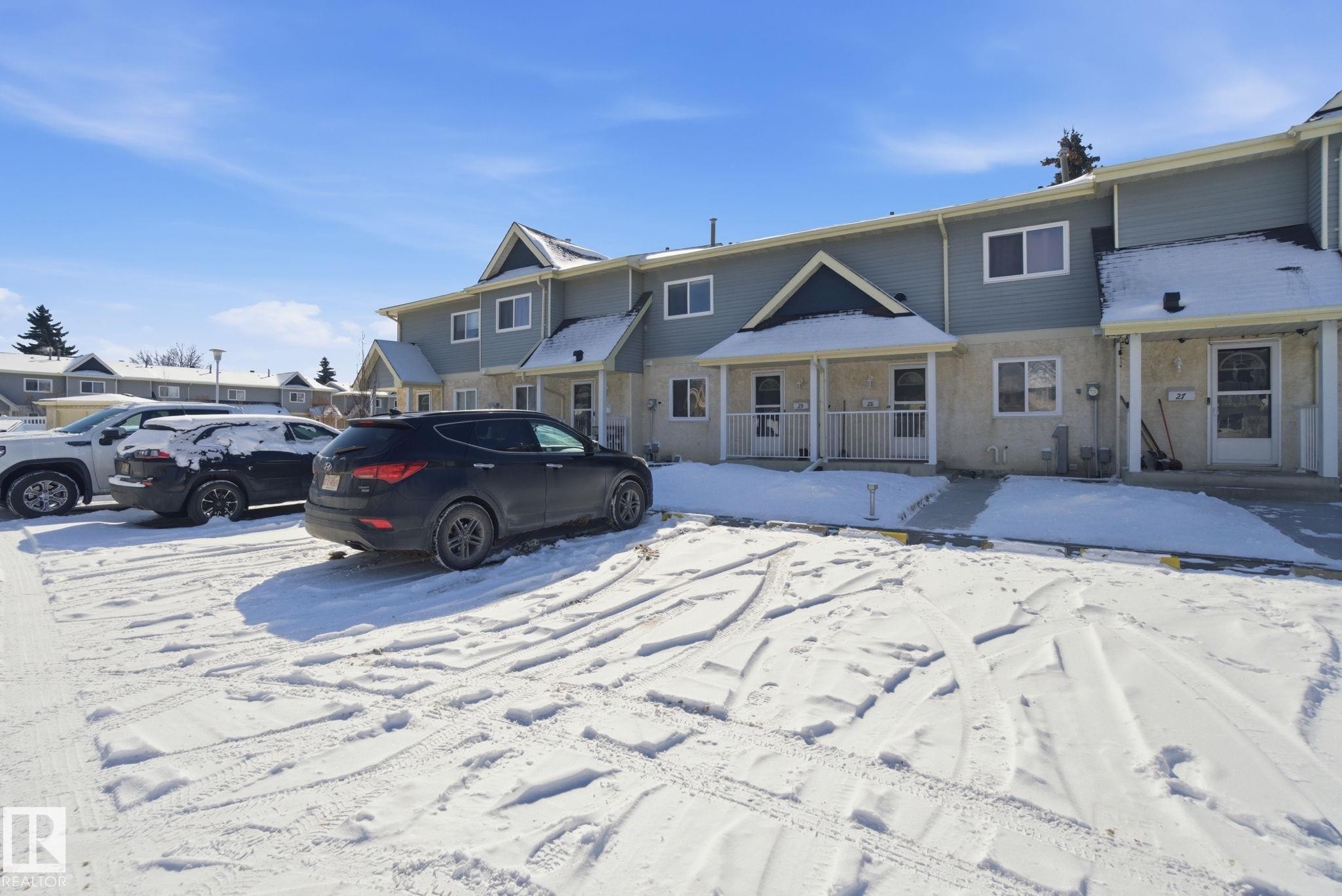 The property features a two-story exterior with light blue siding and light-colored lower-level facade, covered entryways, and white-framed windows - 29 9619 180 Street, Edmonton, AB - Outdoor