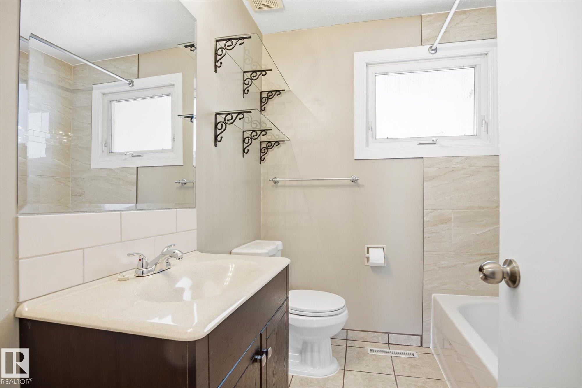 Bathroom featuring a vanity with an integrated sink, a large mirror, and tiled walls in the shower area - 6 Garden Crescent, St. Albert, AB - Indoor Photo Showing Bathroom