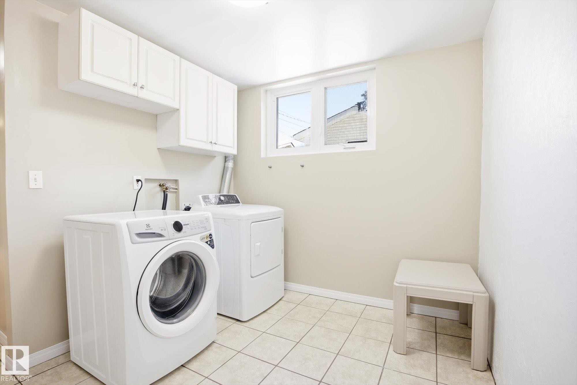 The property features a laundry area with white upper cabinets, a window, and tiled flooring - 6 Garden Crescent, St. Albert, AB - Indoor Photo Showing Laundry Room