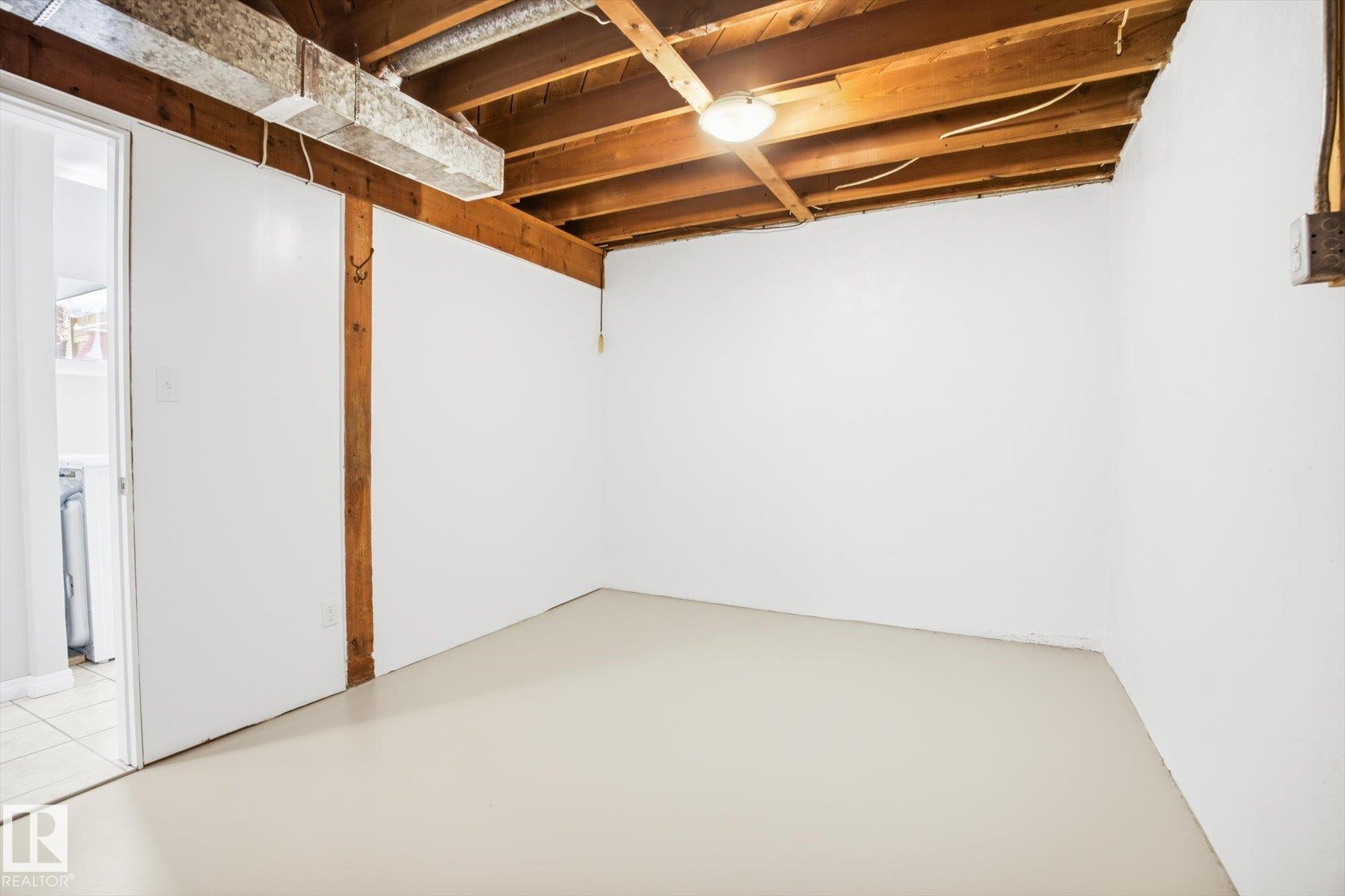 The property features an unfinished room with white walls, exposed wooden ceiling beams, and overhead lighting - 6 Garden Crescent, St. Albert, AB - Indoor Photo Showing Basement