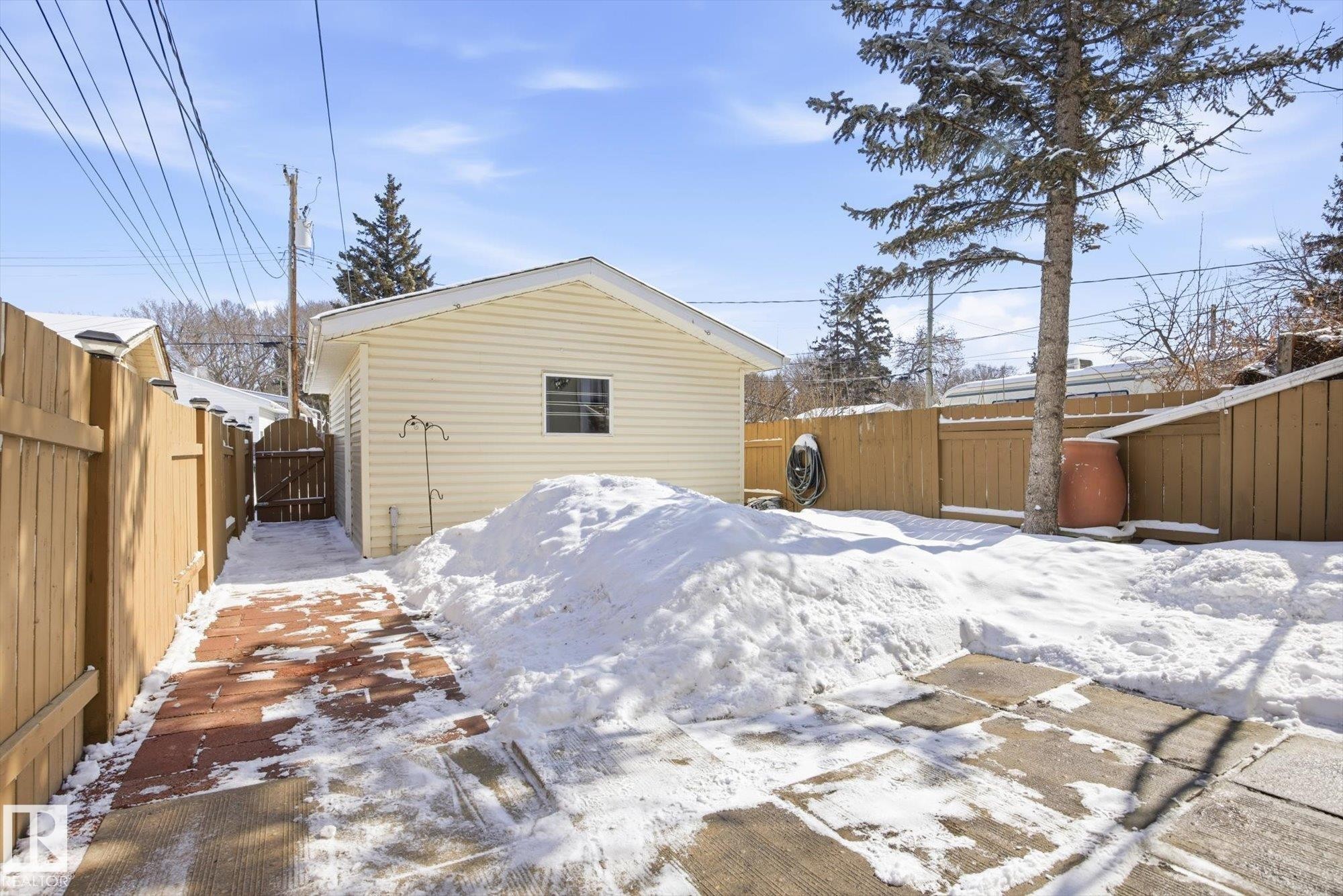 The property features a detached garage with horizontal siding and a window, a wooden fence, and a paved pathway - 6 Garden Crescent, St. Albert, AB - Outdoor