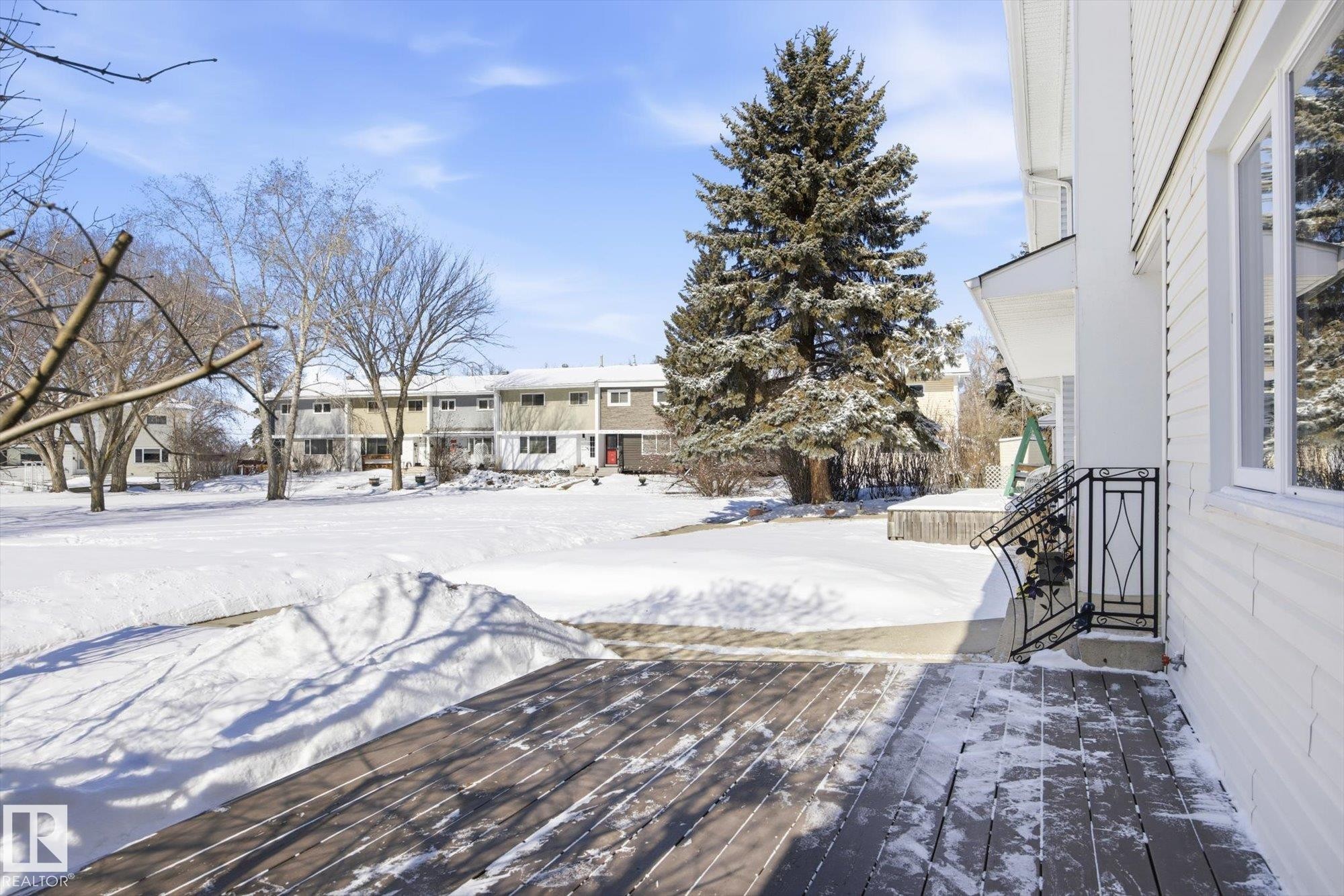 The property features a white exterior with visible windows, a deck, and an ornate black metal railing - 6 Garden Crescent, St. Albert, AB - Outdoor
