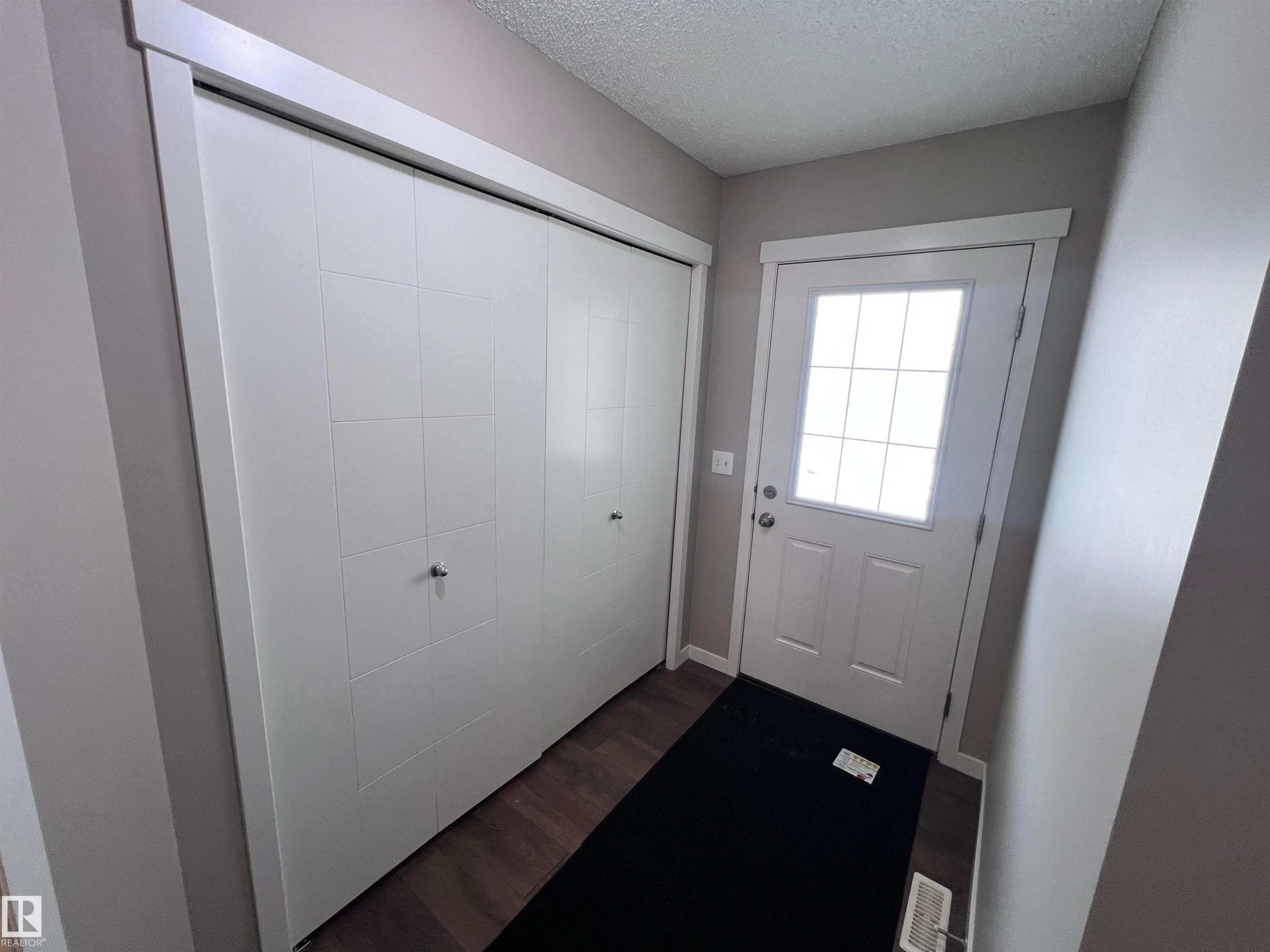 The entryway features a white front door with a window, dark wood flooring, and a spacious closet with white bifold doors - 1421 26 Avenue, Edmonton, AB - Indoor Photo Showing Other Room