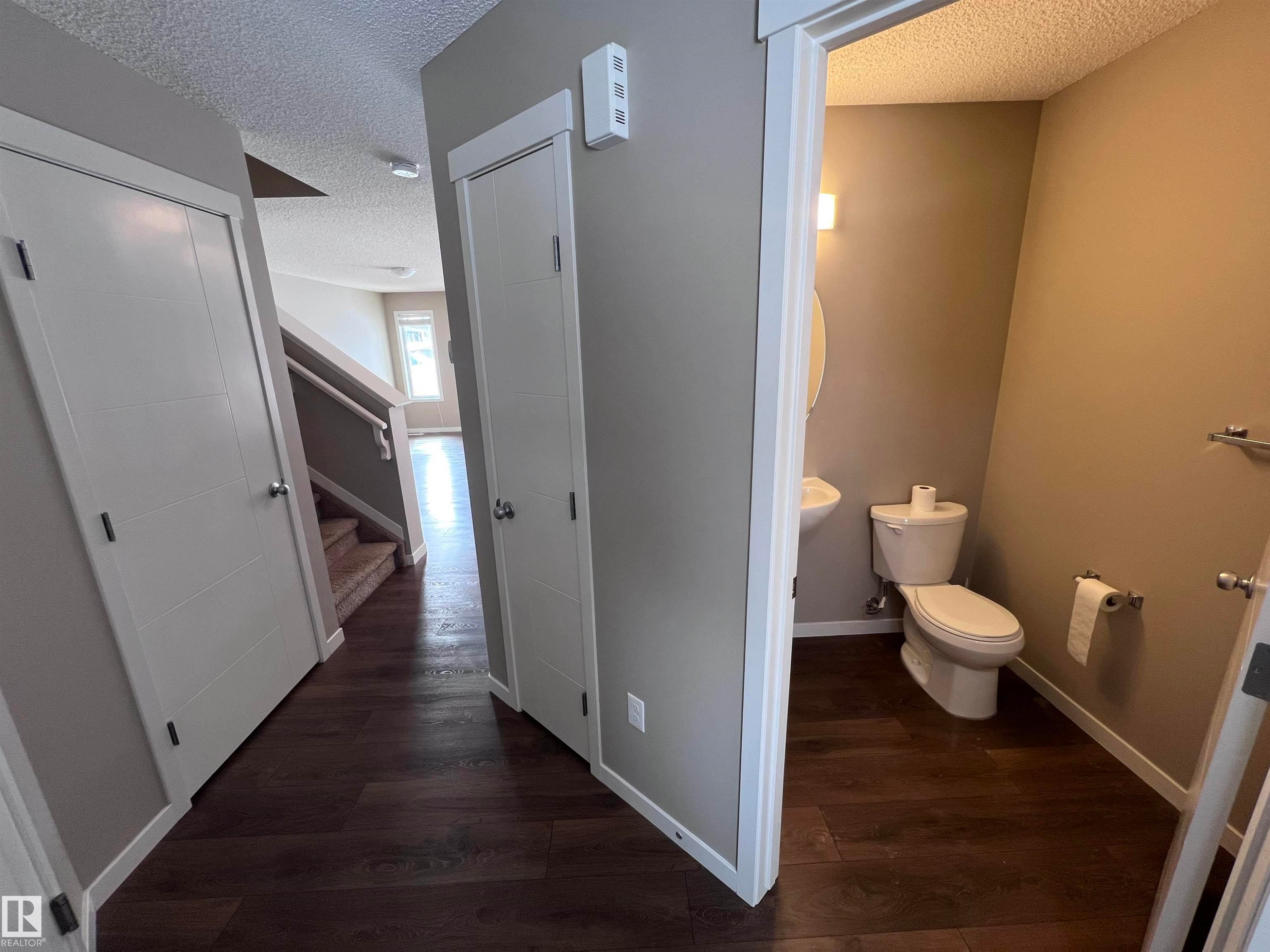 The property features dark hardwood flooring throughout the hallway and into the powder room - 1421 26 Avenue, Edmonton, AB - Indoor Photo Showing Bathroom