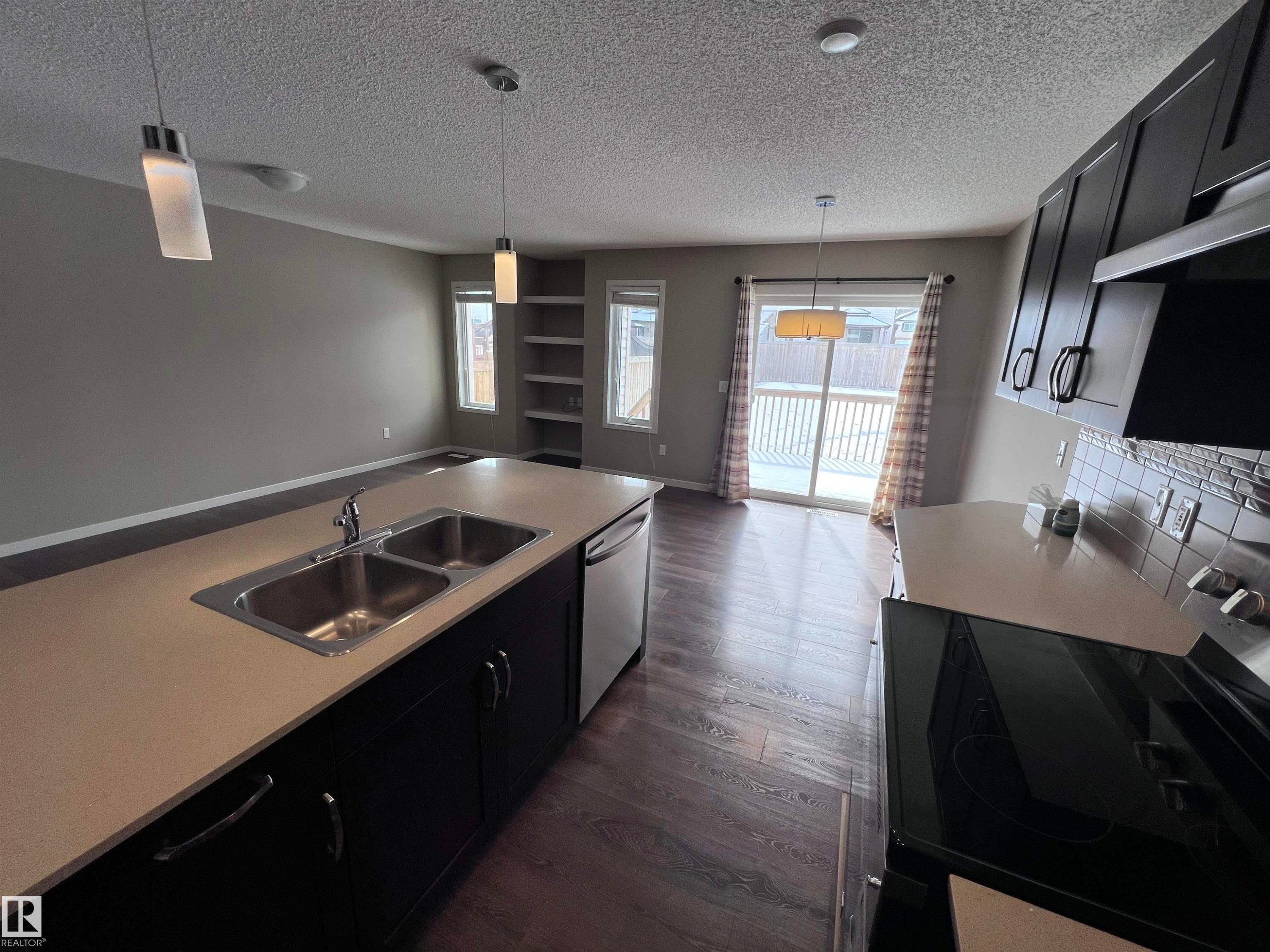 The kitchen features dark cabinetry, a double basin sink, and a dishwasher - 1421 26 Avenue, Edmonton, AB - Indoor Photo Showing Kitchen With Double Sink