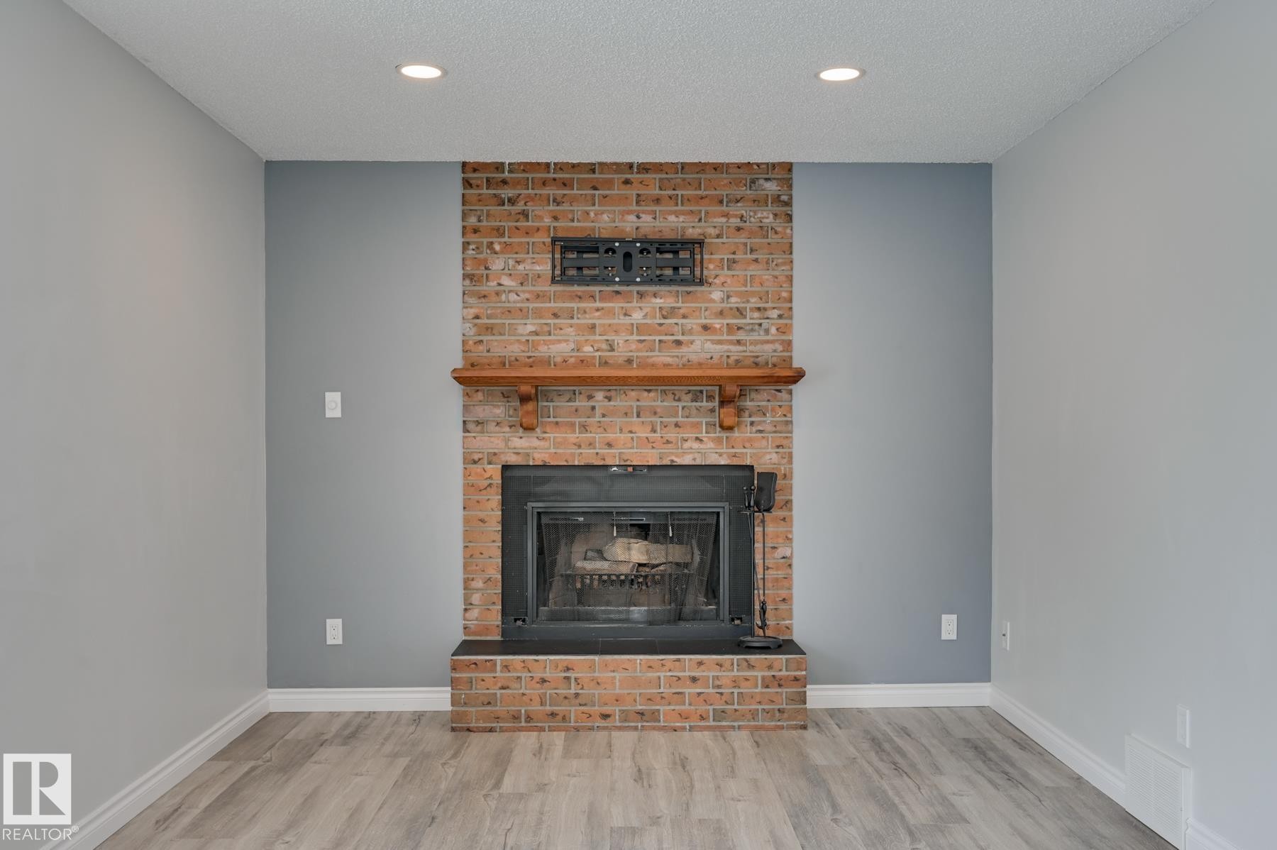 Living area featuring a brick fireplace with a wood mantel, recessed lighting, and light-toned flooring - 8507 152B Avenue, Edmonton, AB - Indoor Photo Showing Living Room With Fireplace