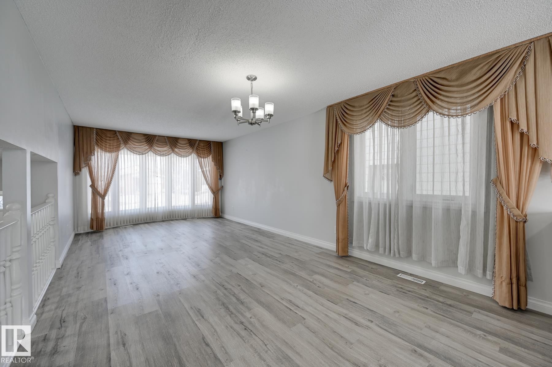 The property features light-toned flooring, white walls, and a multi-pane window with sheer curtains and draped valances - 8507 152B Avenue, Edmonton, AB - Indoor Photo Showing Other Room