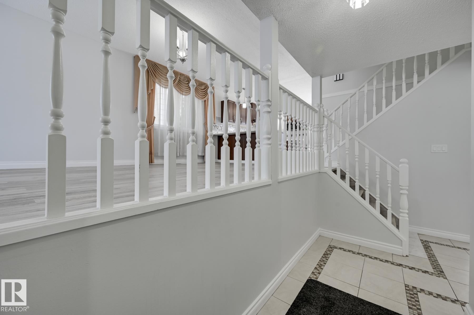 Entryway featuring a white wooden staircase and a tiled floor with a decorative border - 8507 152B Avenue, Edmonton, AB - Indoor Photo Showing Other Room