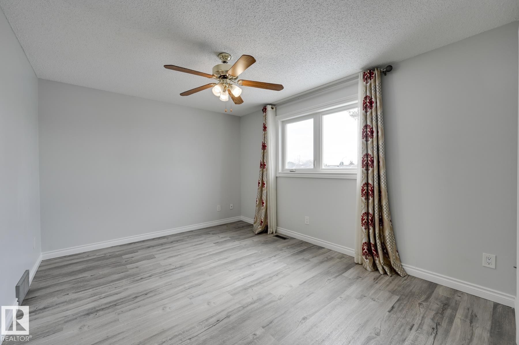 This room features light grey walls, light grey flooring, and a ceiling fan with integrated lighting - 8507 152B Avenue, Edmonton, AB - Indoor Photo Showing Other Room