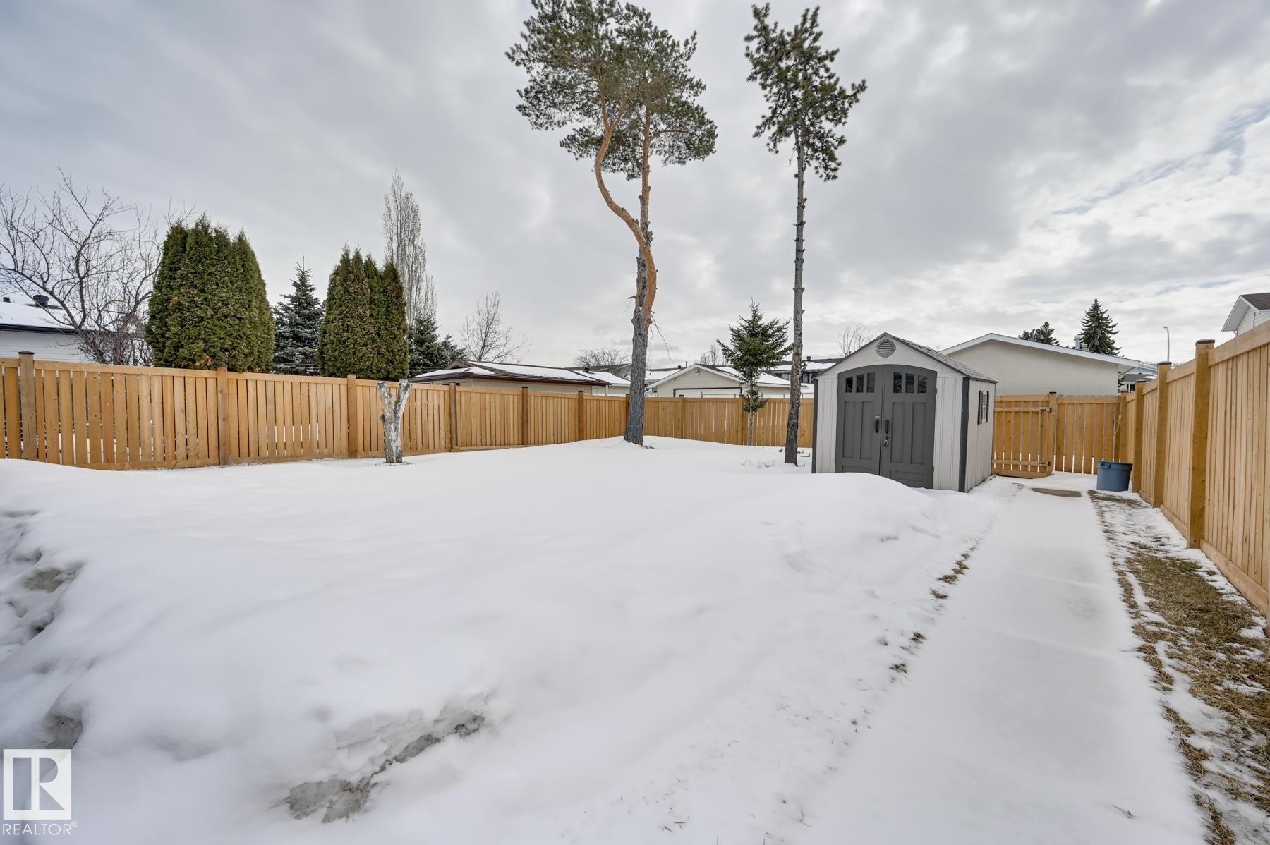 The property features a fully fenced yard with a storage shed and mature trees - 8507 152B Avenue, Edmonton, AB - Outdoor