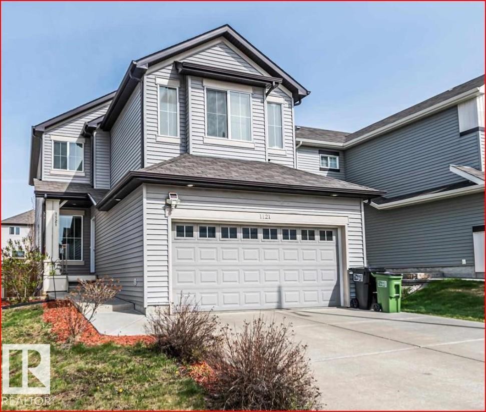 Two-story property featuring light gray siding, a two-car garage, dark-shingled roof, and a concrete driveway - 1121 59A Street, Edmonton, AB - Outdoor
