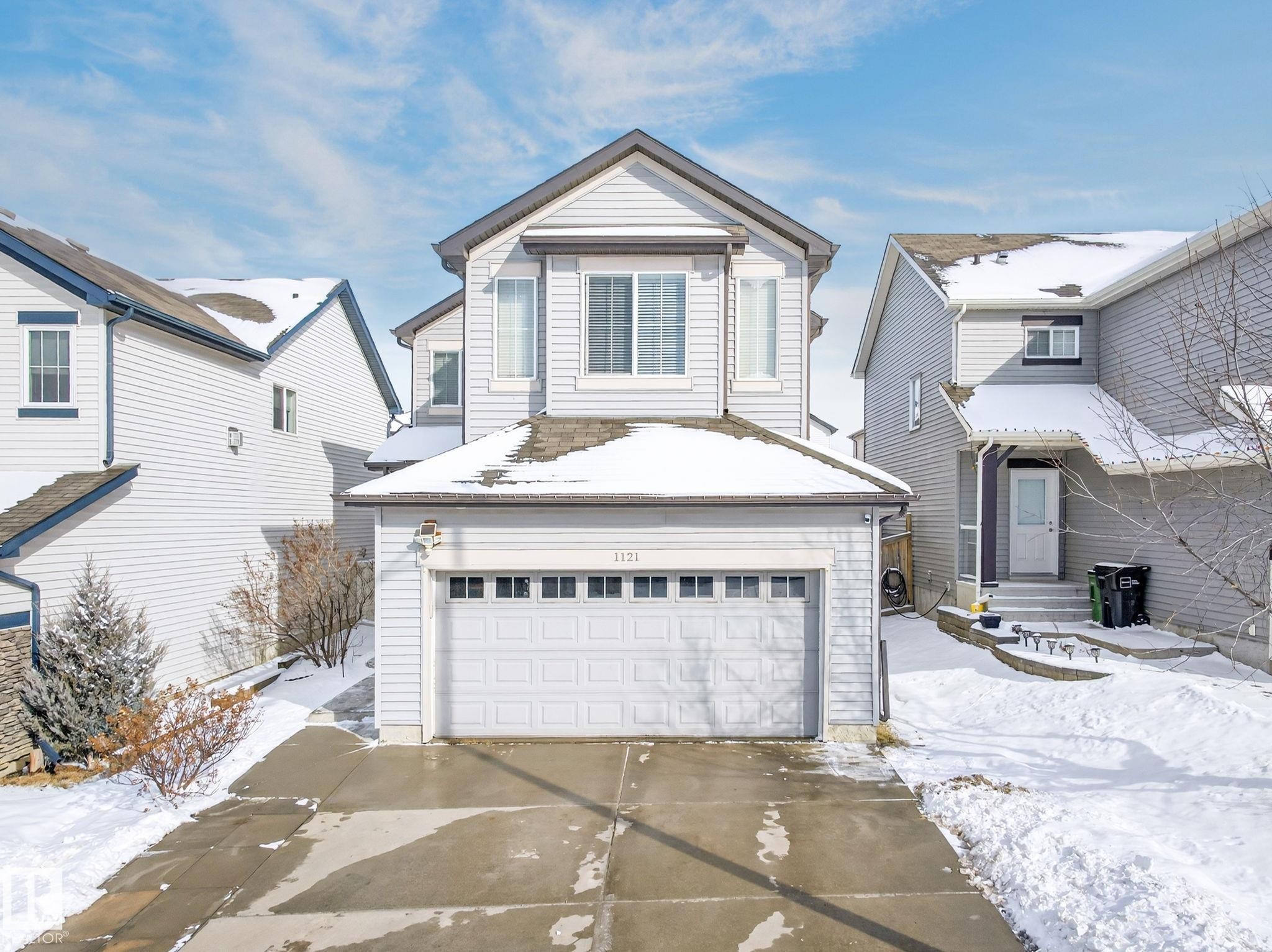The property features a two-story residence with light-colored siding and a front-facing garage - 1121 59A Street, Edmonton, AB - Outdoor