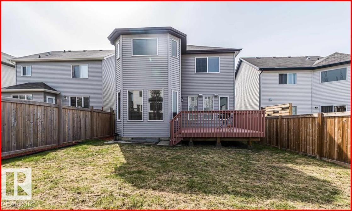 Expansive backyard featuring a wood deck with railing, full privacy fencing, and a multi-level siding exterior with multiple windows - 1121 59A Street, Edmonton, AB - Outdoor With Deck Patio Veranda