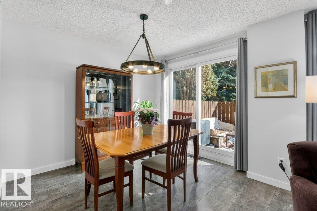 Dining area featuring a contemporary chandelier and sliding glass doors that open to fenced an outdoor space - 91 Hearthstone, Edmonton, AB - Indoor Photo Showing Dining Room