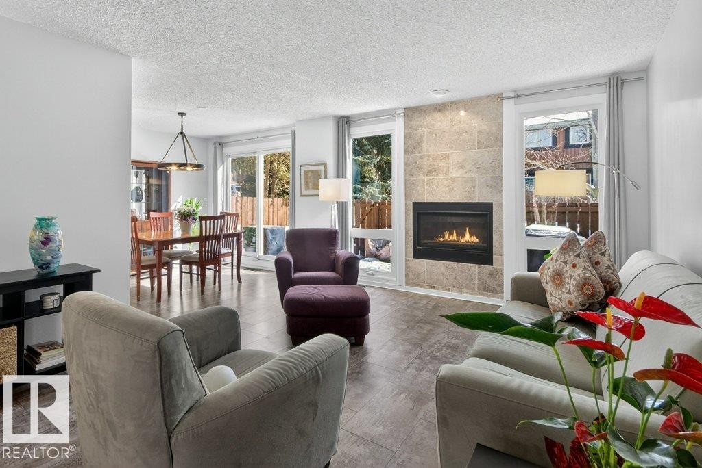 Living area featuring a gas fireplace & large windows providing natural light - 91 Hearthstone, Edmonton, AB - Indoor Photo Showing Living Room With Fireplace