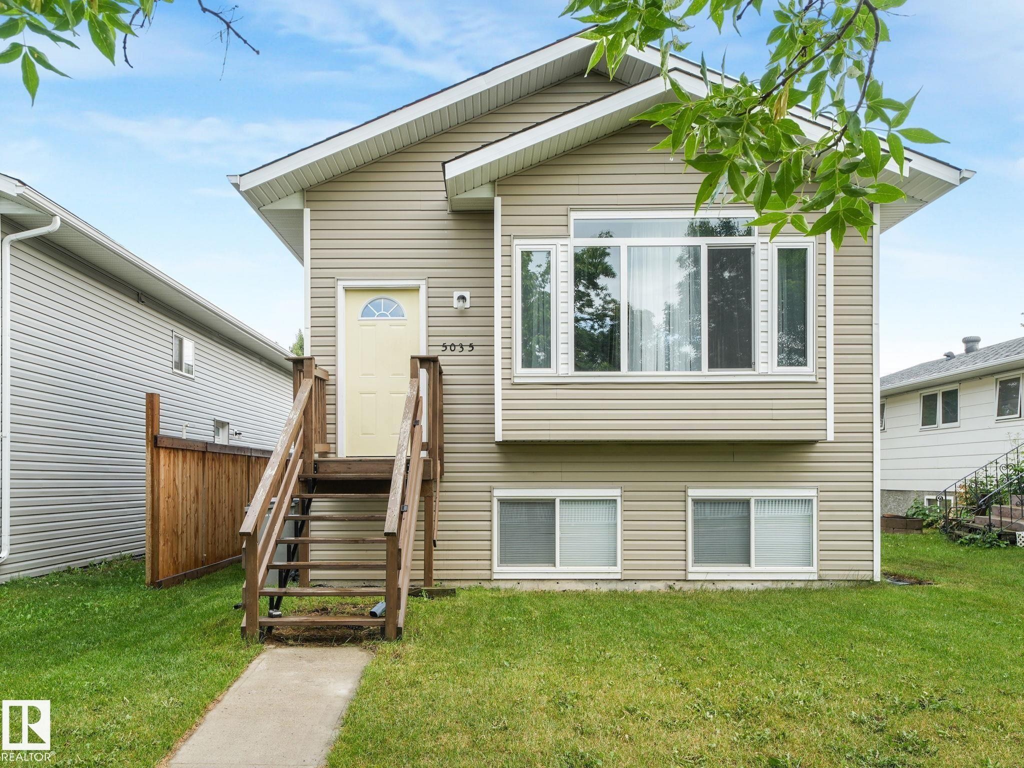 Split-level residence featuring beige vinyl siding and a gable roof with white trim - 5035 51 Avenue, Lamont, AB - Outdoor