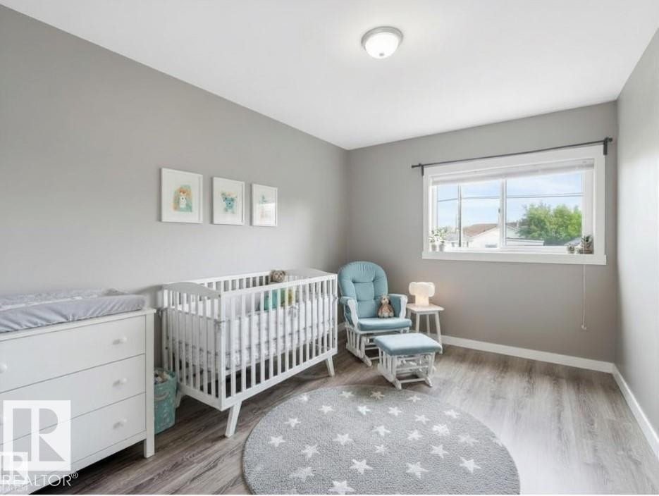 Bedroom with light grey walls, grey wood-style flooring, and a window providing natural light - 5035 51 Avenue, Lamont, AB - Indoor Photo Showing Bedroom