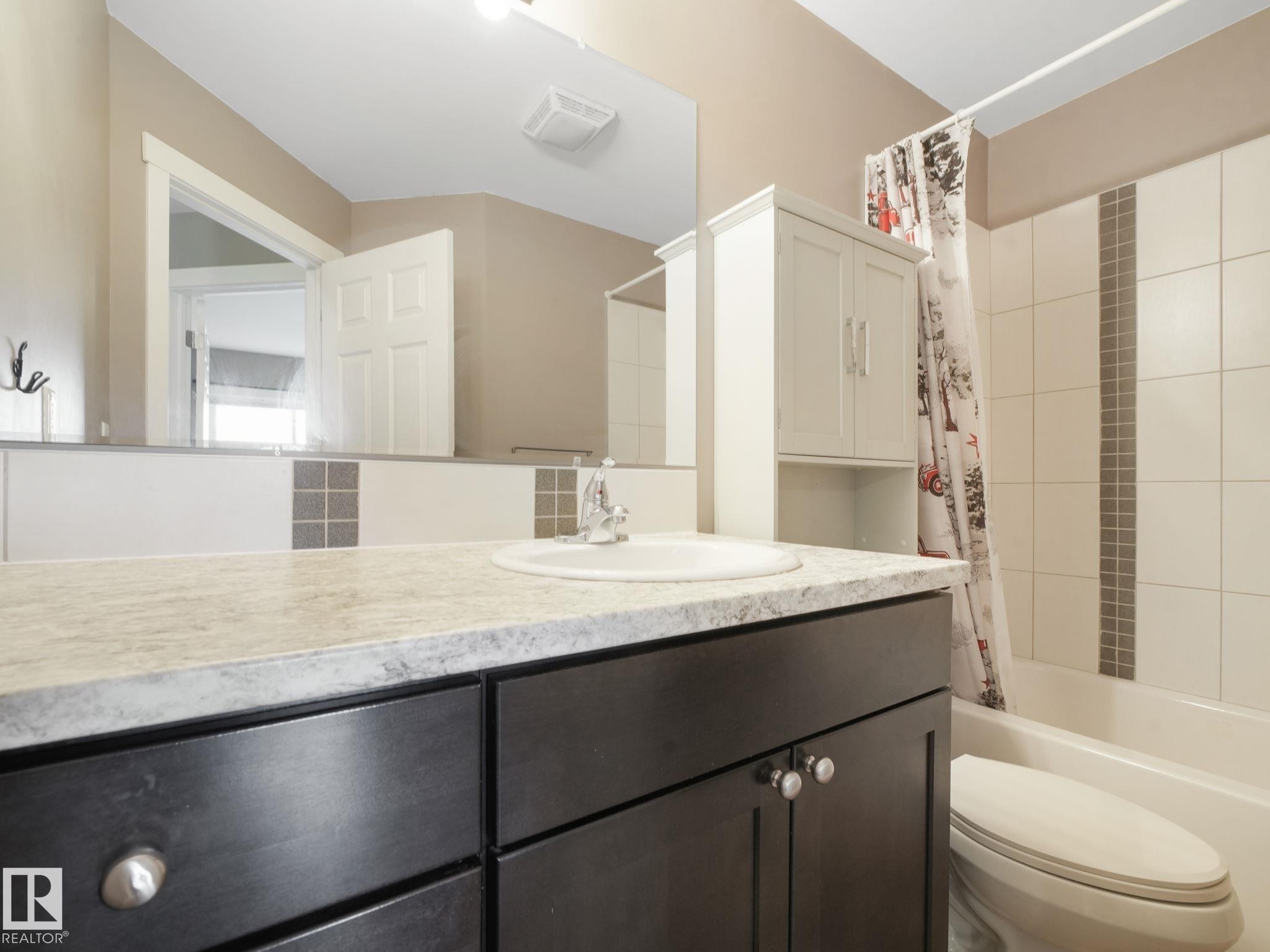 Bathroom featuring a vanity with a light-colored countertop, dark cabinetry, and a round sink basin - 5035 51 Avenue, Lamont, AB - Indoor Photo Showing Bathroom