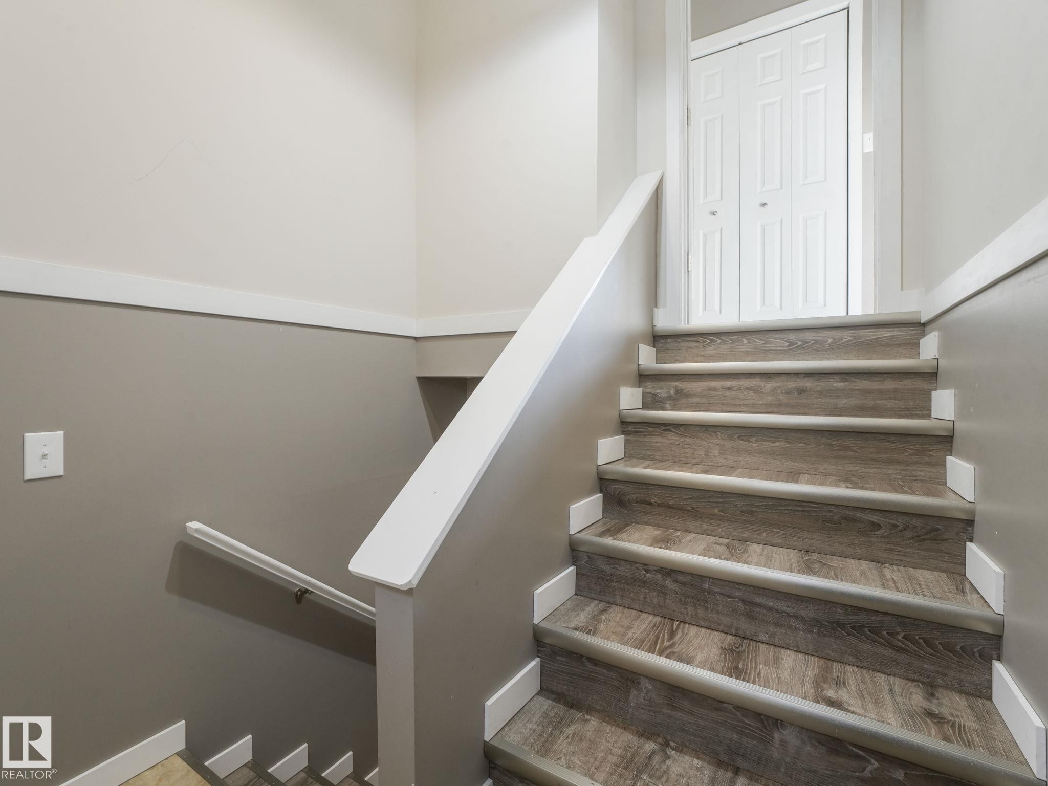 The staircase features wood-look treads, white risers, and a white handrail - 5035 51 Avenue, Lamont, AB - Indoor Photo Showing Other Room