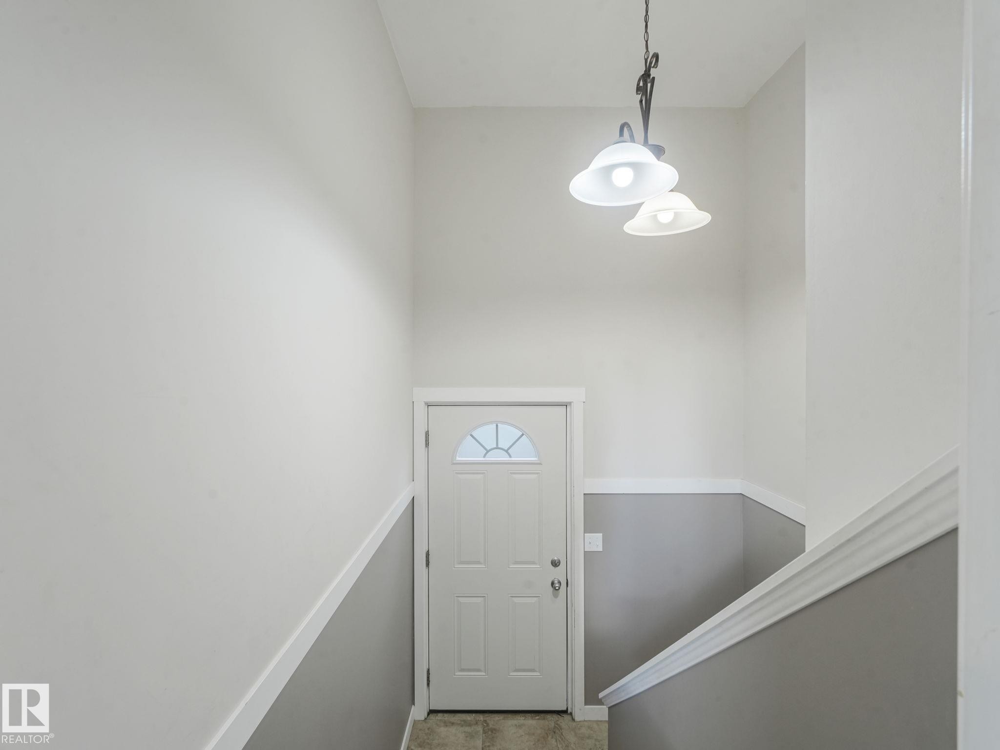 Entryway featuring a white door with a decorative window, a two-tone painted wall, and an overhead light fixture - 5035 51 Avenue, Lamont, AB - Indoor Photo Showing Other Room