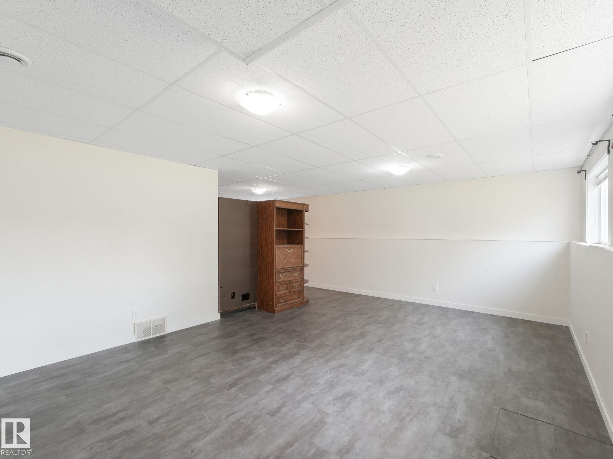 Spacious room featuring light gray flooring, white walls, and a white ceiling with flush-mount lighting fixtures - 5035 51 Avenue, Lamont, AB - Indoor