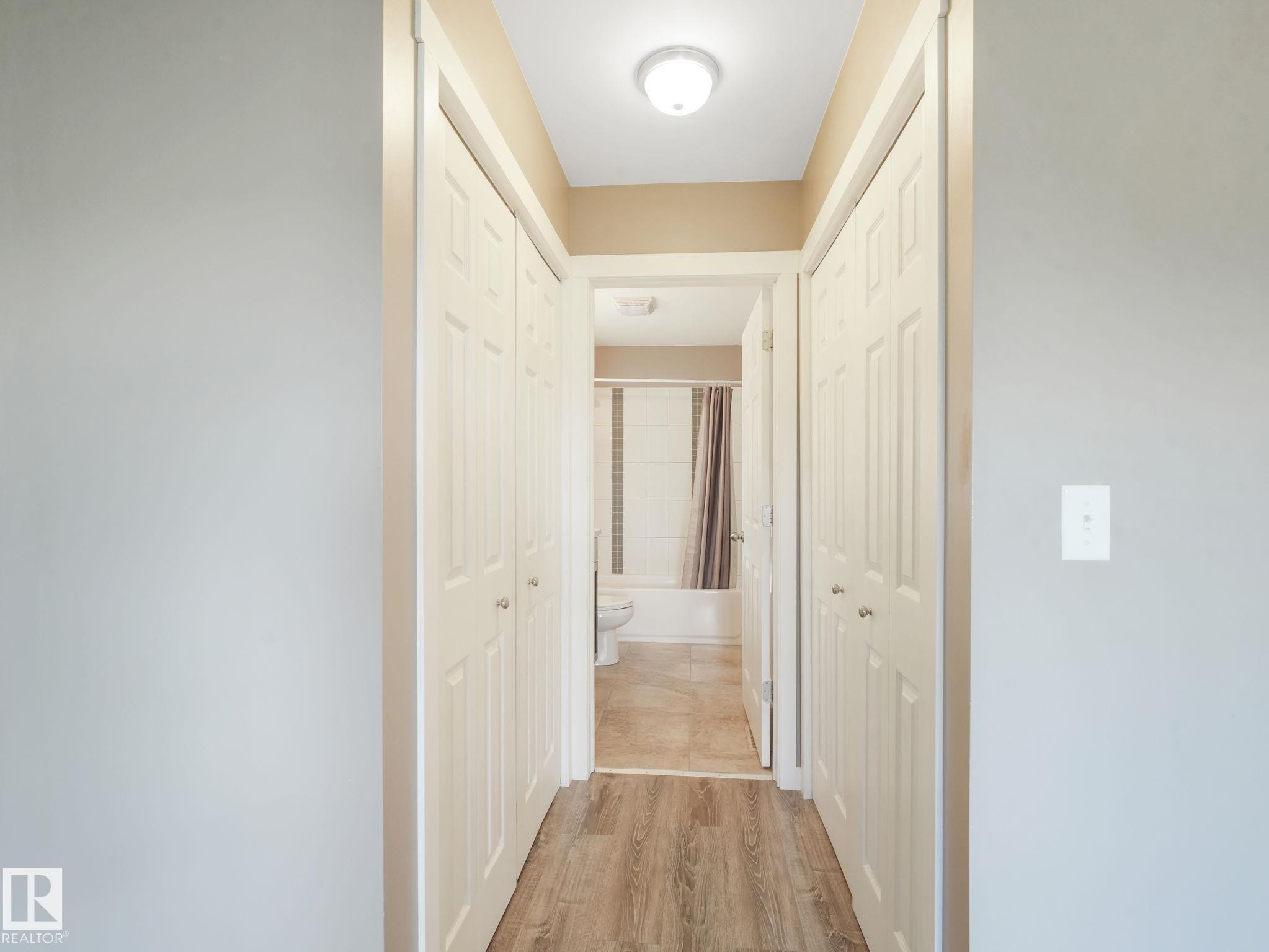 Hallway with light wood-style flooring, white paneled bifold doors, and a ceiling-mounted light fixture - 5035 51 Avenue, Lamont, AB - Indoor Photo Showing Other Room