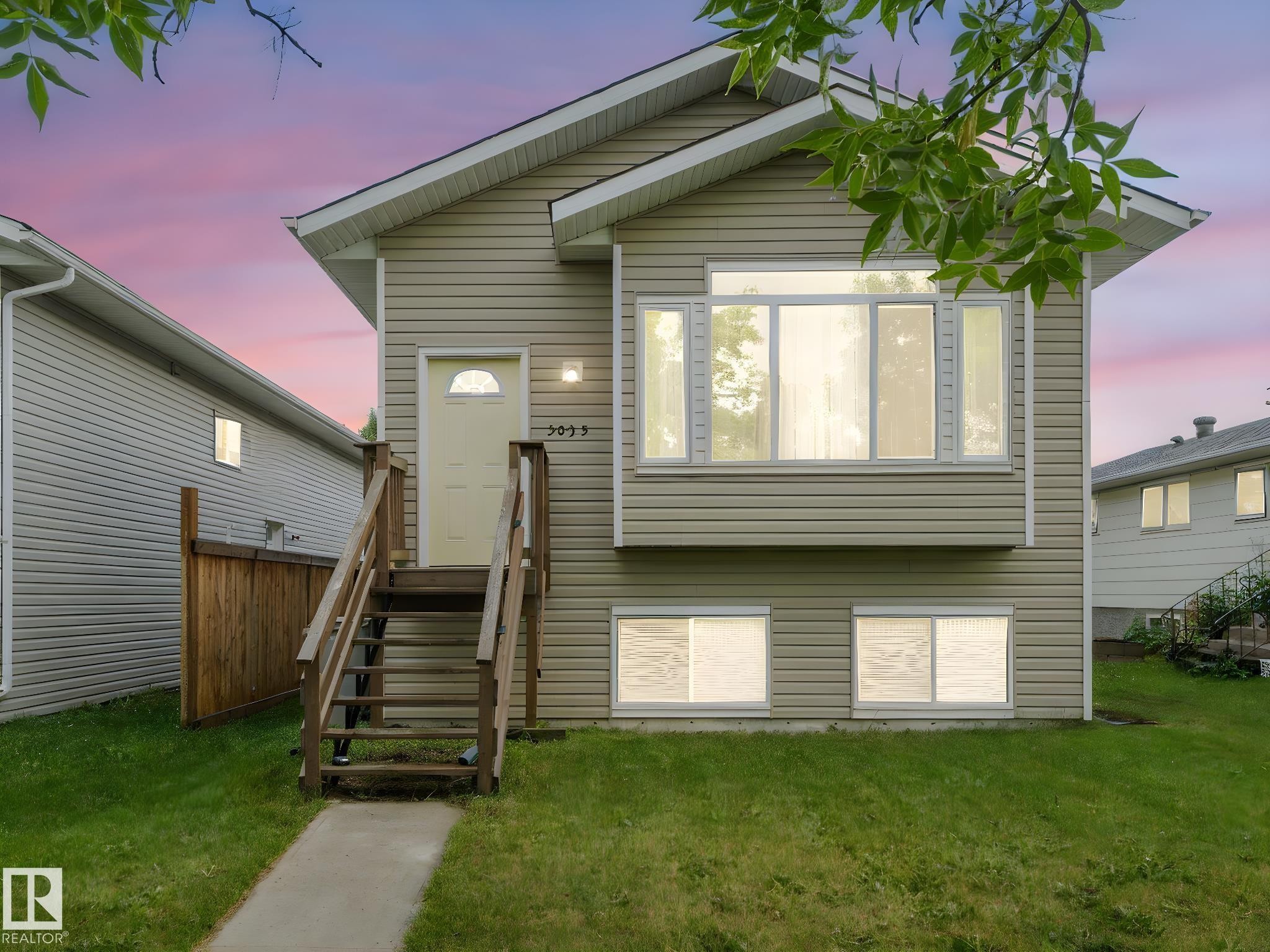 The property features a light-colored exterior with a front entry staircase and a front yard with a lawn and sidewalk - 5035 51 Avenue, Lamont, AB - Outdoor