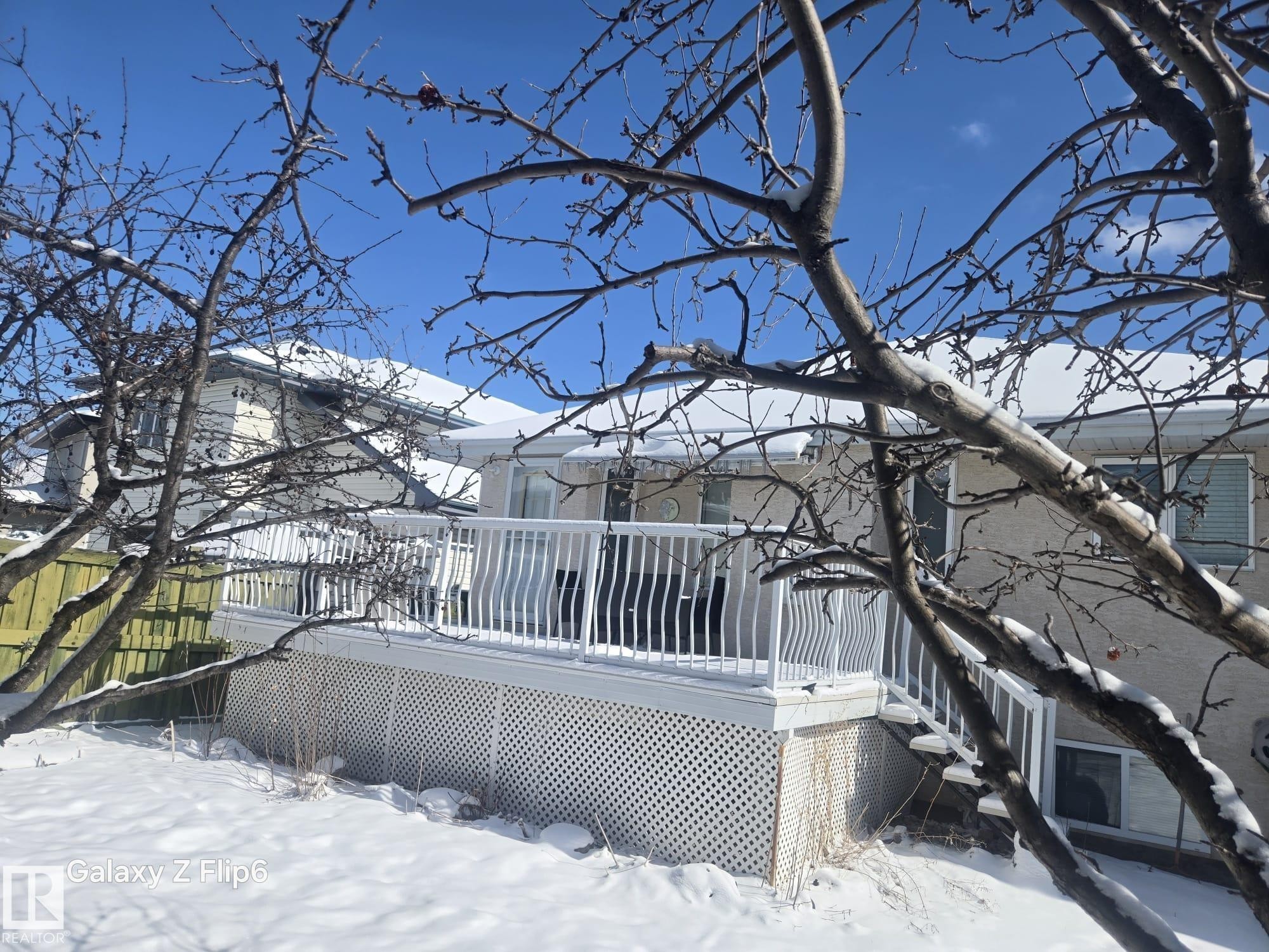 The property features an exterior deck with white railings and lattice skirting, accessible via stairs - Edmonton, AB - Outdoor