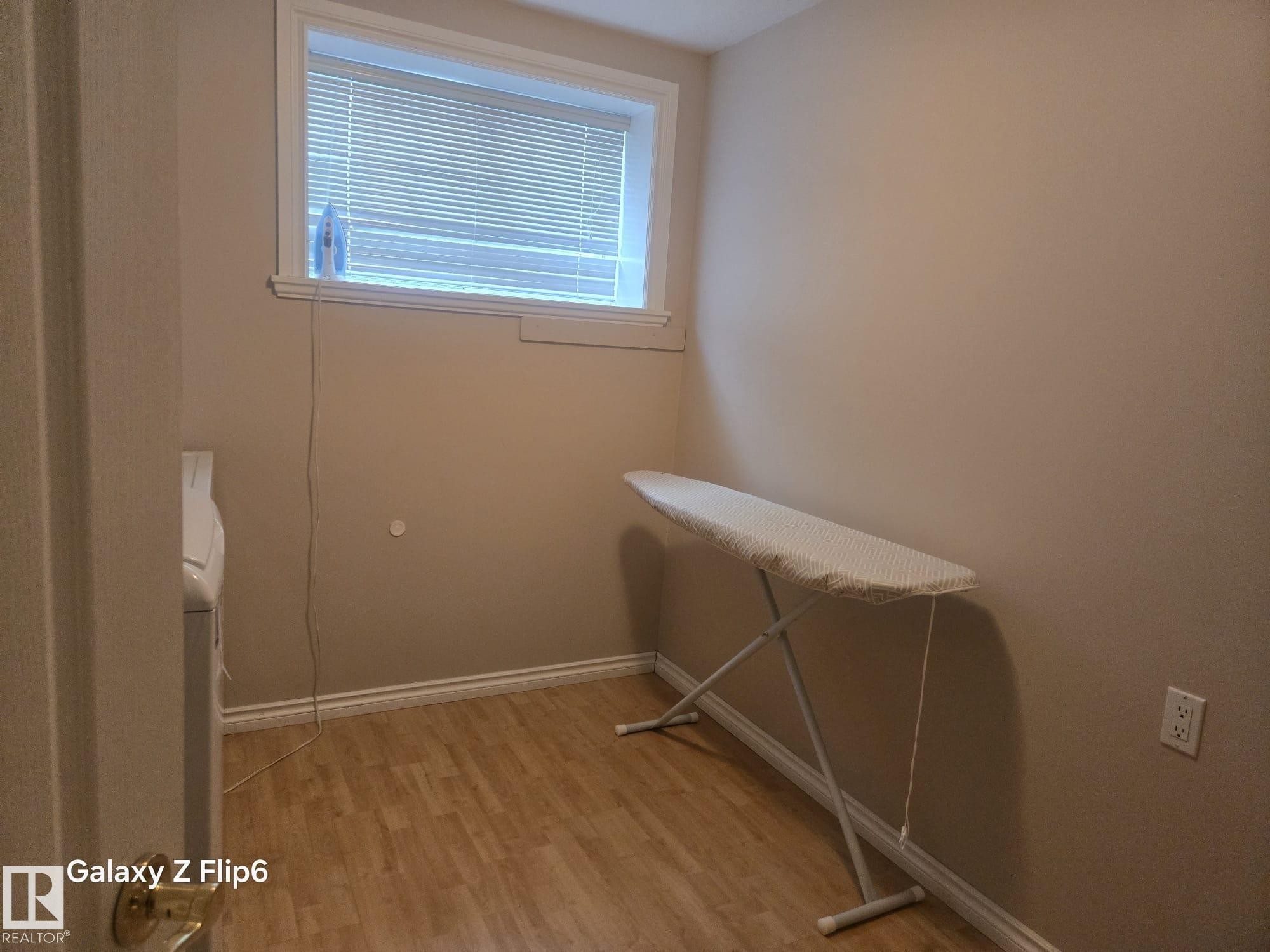 The property features a dedicated space with wood-look flooring and a window with blinds - Edmonton, AB - Indoor Photo Showing Other Room
