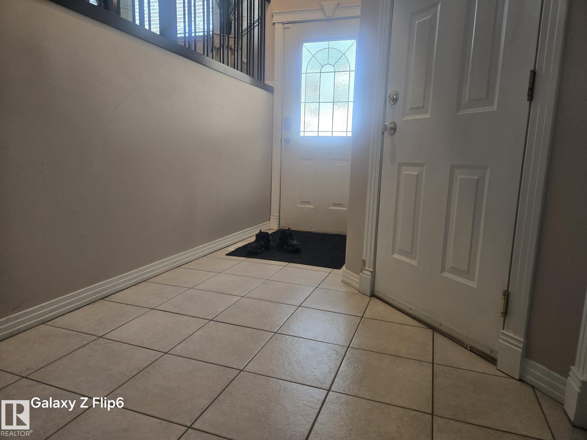 Entryway featuring light-colored tile flooring, a white paneled door, and a front door with a decorative glass insert - Edmonton, AB - Indoor Photo Showing Other Room