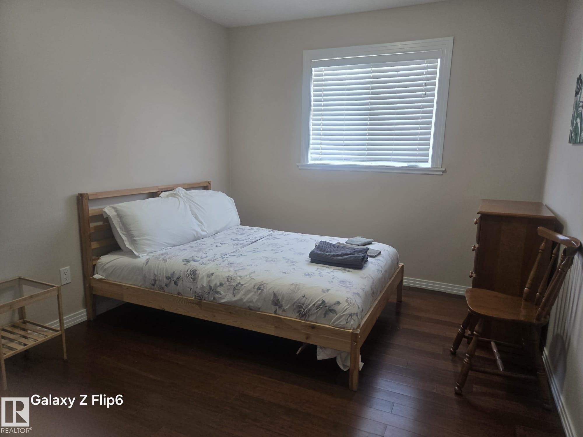 Bedroom featuring dark hardwood flooring, a window with blinds, and light-colored walls - Edmonton, AB - Indoor Photo Showing Bedroom