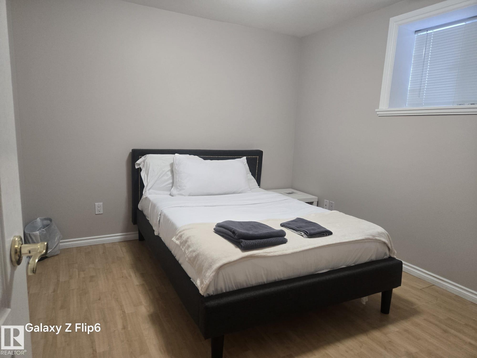 This room features light-colored walls and wood-look flooring - Edmonton, AB - Indoor Photo Showing Bedroom