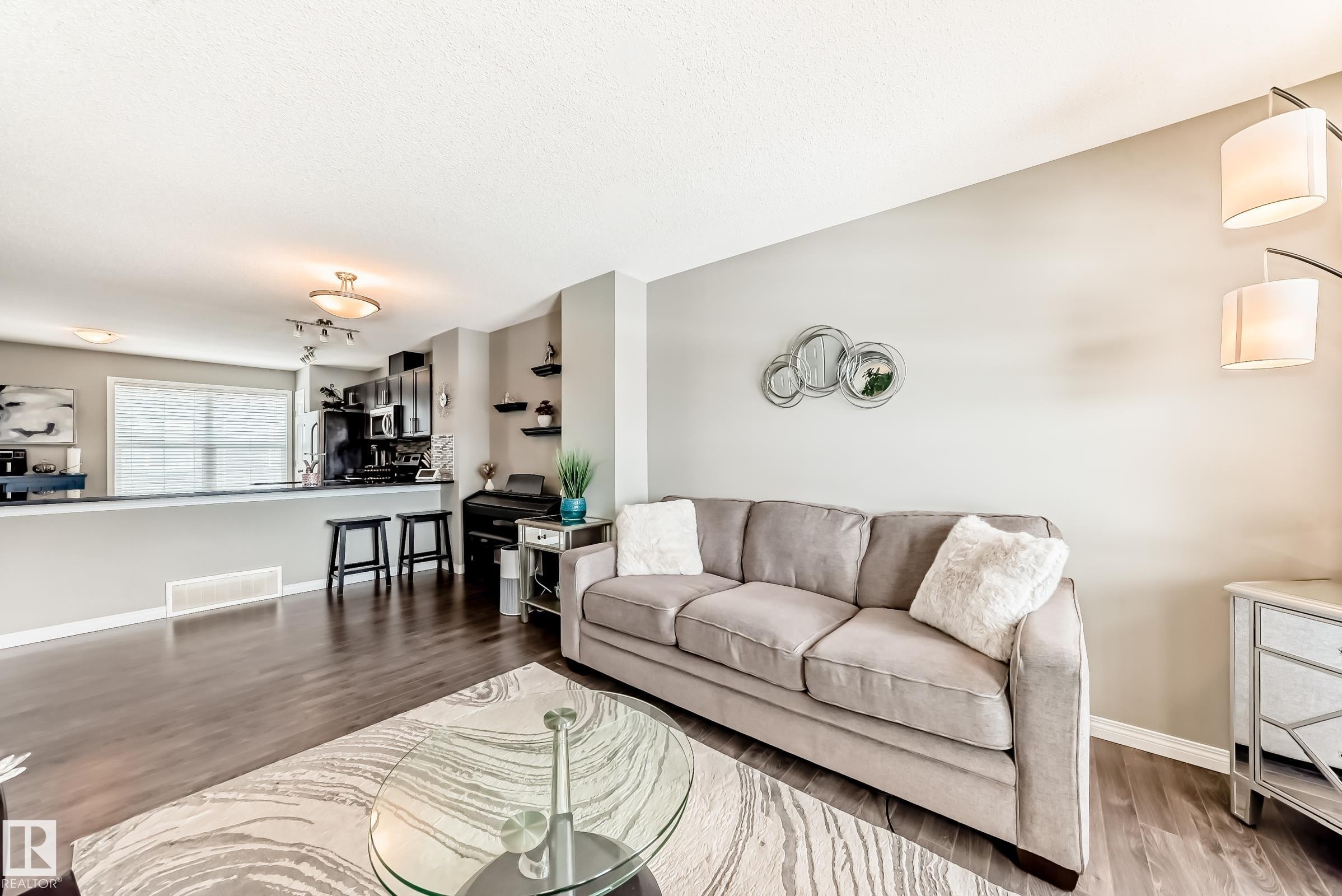 Living room featuring dark wood flooring, light grey walls, and a glass-top coffee table - 86 4029 Orchards Drive, Edmonton, AB - Indoor Photo Showing Living Room