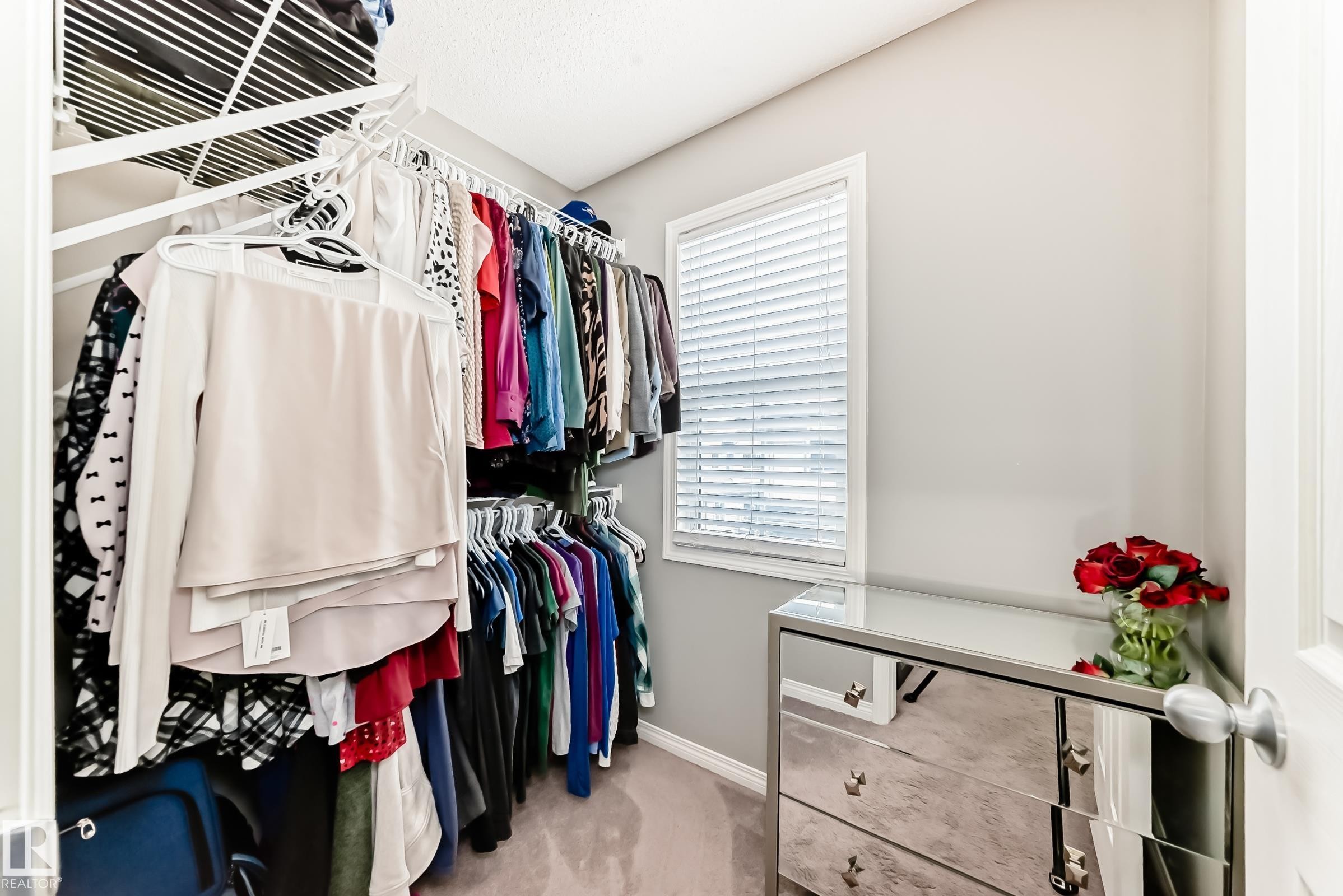 The property features a walk-in closet with ample hanging space and shelving, a window with blinds, and carpeting - 86 4029 Orchards Drive, Edmonton, AB - Indoor With Storage