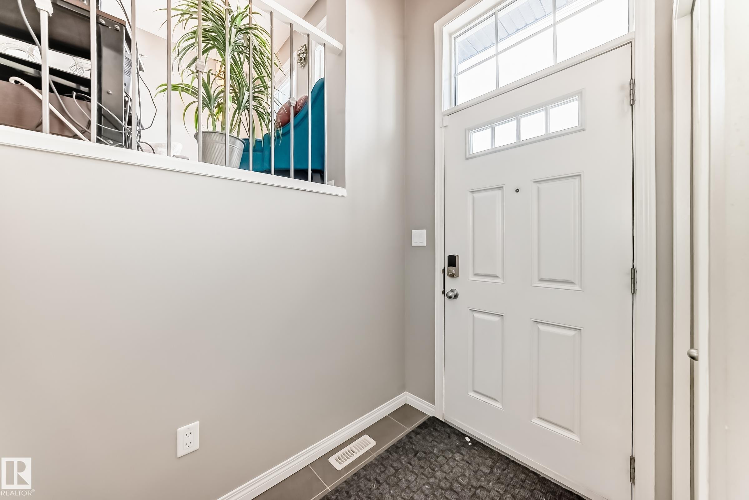 The property features a front entrance with a white paneled door, transom window, and tiled flooring - 86 4029 Orchards Drive, Edmonton, AB - Indoor Photo Showing Other Room