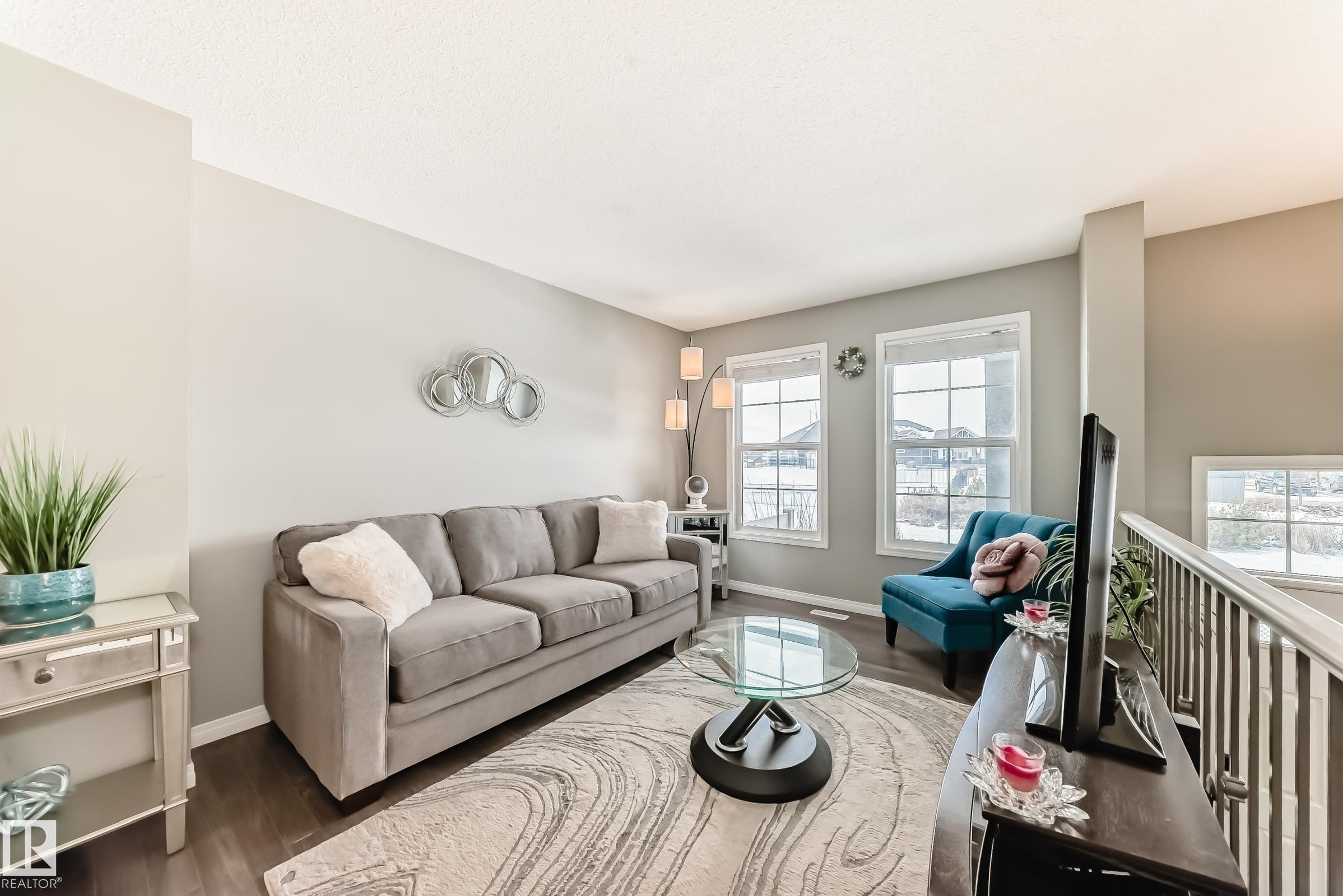 Living area featuring dark flooring, light-colored walls, and large windows providing natural light - 86 4029 Orchards Drive, Edmonton, AB - Indoor Photo Showing Living Room