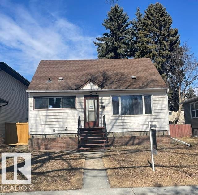 The property features a traditional facade with white siding and a brown shingle roof - 7934 81 Avenue, Edmonton, AB
