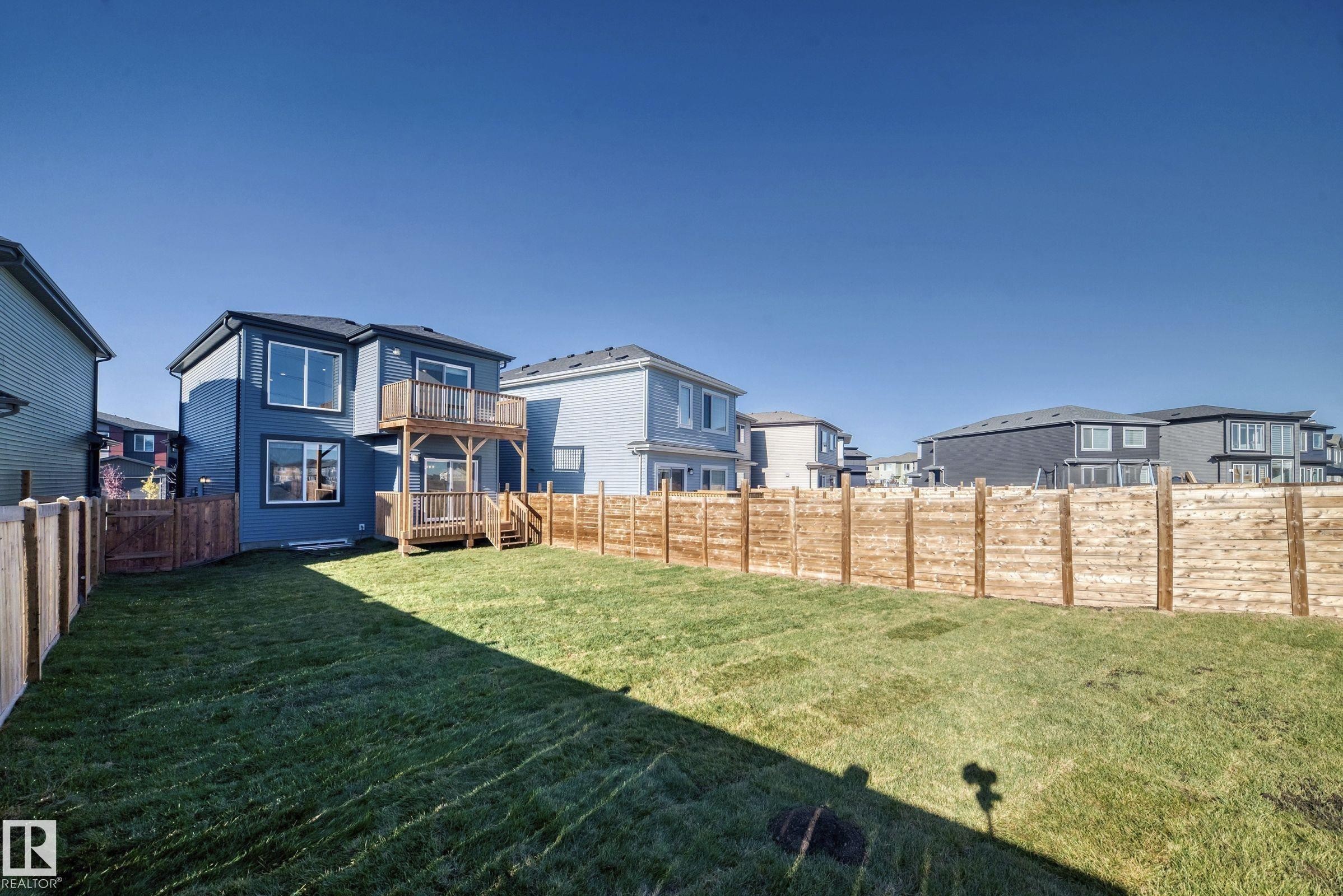 The property features an extensive backyard with a well-maintained lawn, privacy fencing, and a two-story wooden deck - 9411 Pear Crescent, Edmonton, AB - Outdoor With Deck Patio Veranda