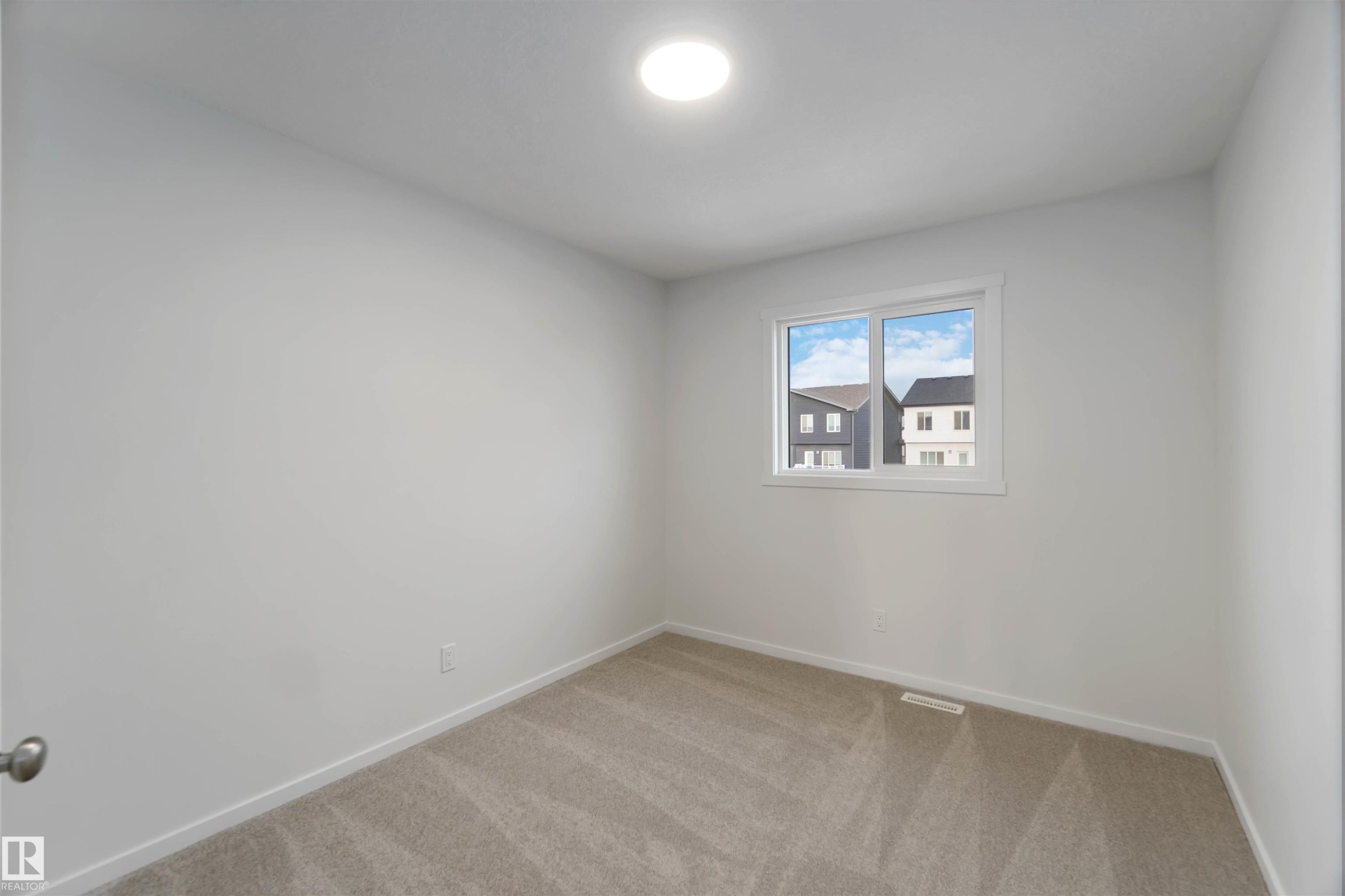 This room features neutral-toned carpet, white walls, and a window providing natural light - 5452 Hawthorn Run, Edmonton, AB - Indoor Photo Showing Other Room