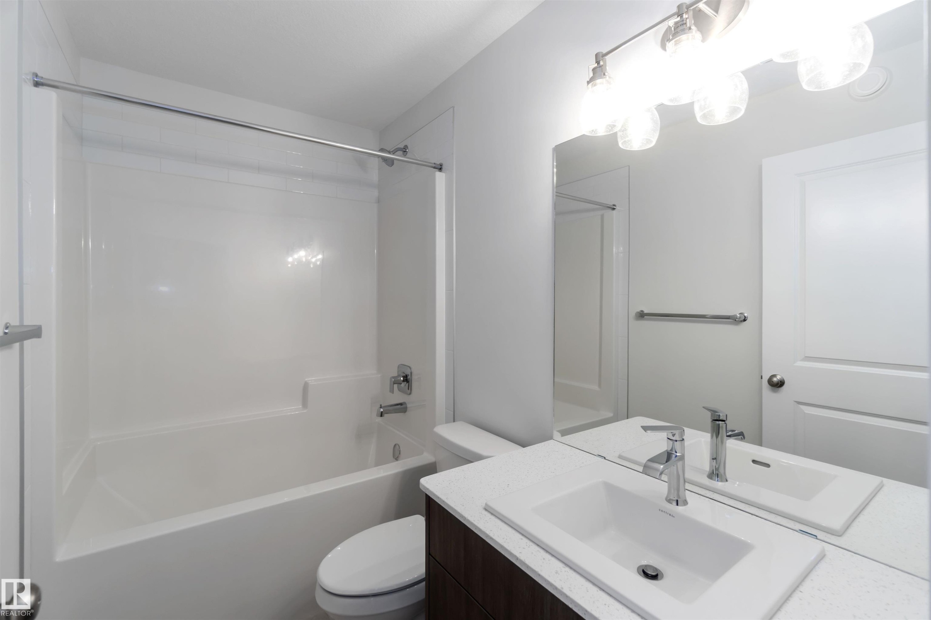 The bathroom features a vanity with a rectangular sink, a polished chrome faucet, and a large mirror with a four-light fixture - 5452 Hawthorn Run, Edmonton, AB - Indoor Photo Showing Bathroom