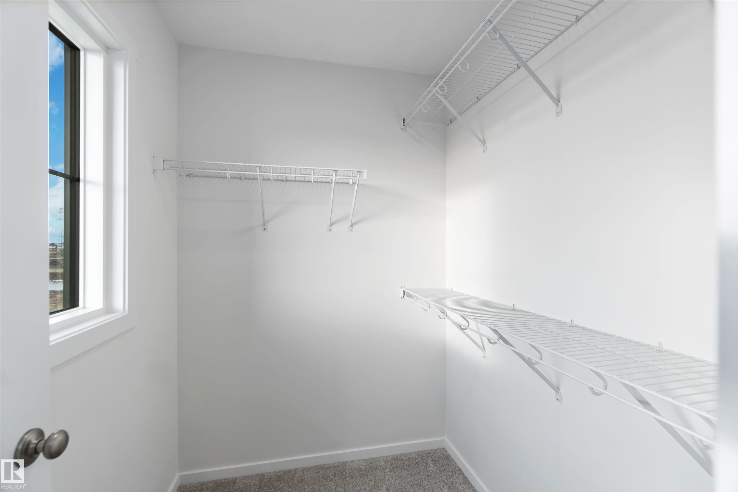 This closet features a window providing natural light, wire shelving, and wire hanging rods - 5452 Hawthorn Run, Edmonton, AB - Indoor With Storage