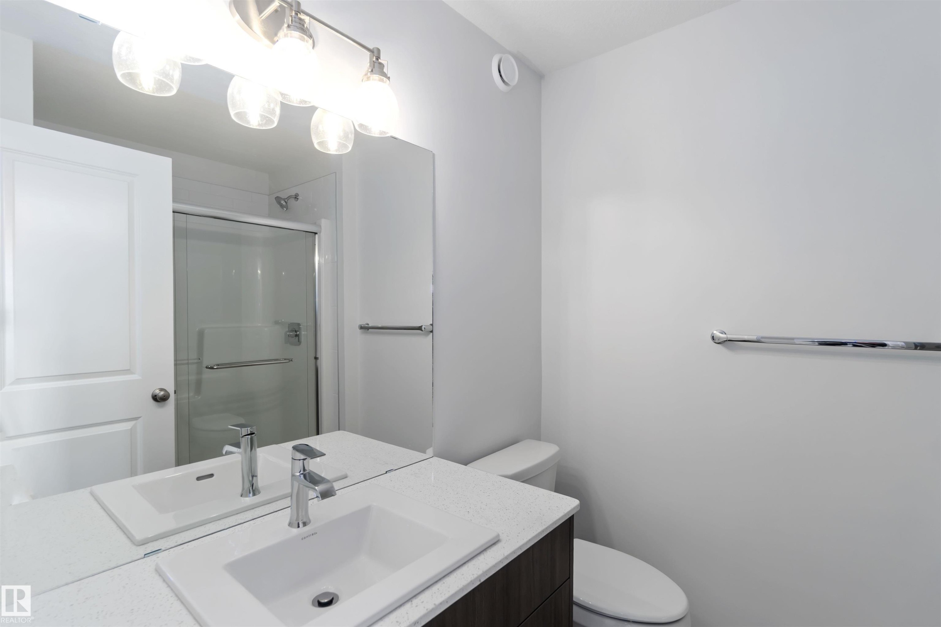 Bathroom featuring a vanity with an undermount sink, a chrome faucet, and a large mirror with overhead lighting - 5452 Hawthorn Run, Edmonton, AB - Indoor Photo Showing Bathroom