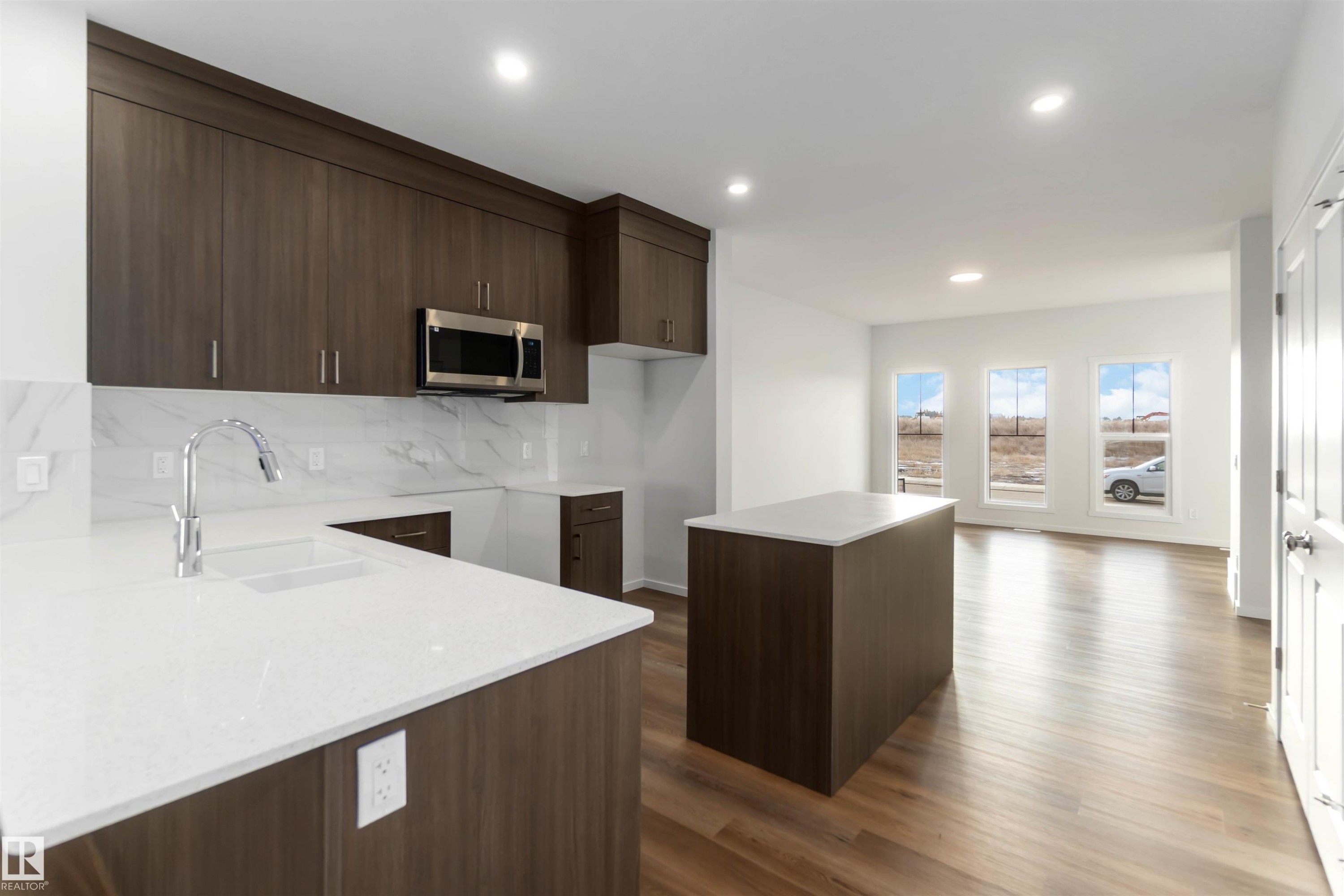 The kitchen features dark wood cabinetry, white countertops, a stainless steel microwave, and a white tile backsplash - 5452 Hawthorn Run, Edmonton, AB - Indoor Photo Showing Kitchen